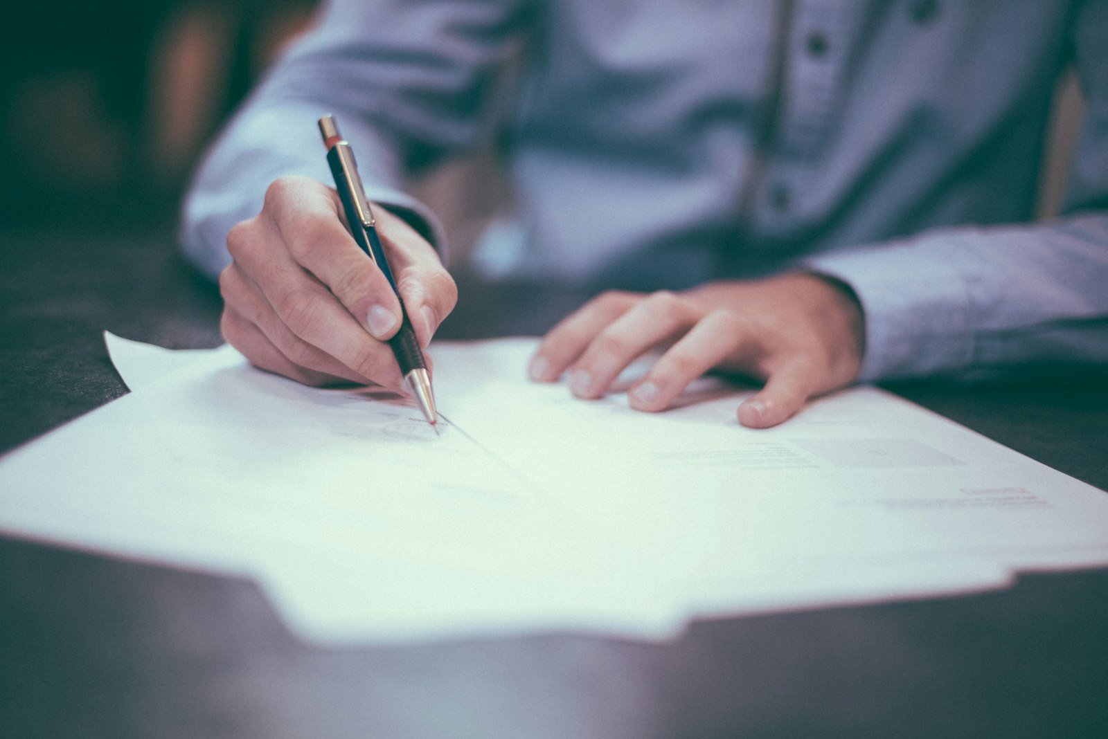 A hand signing a document