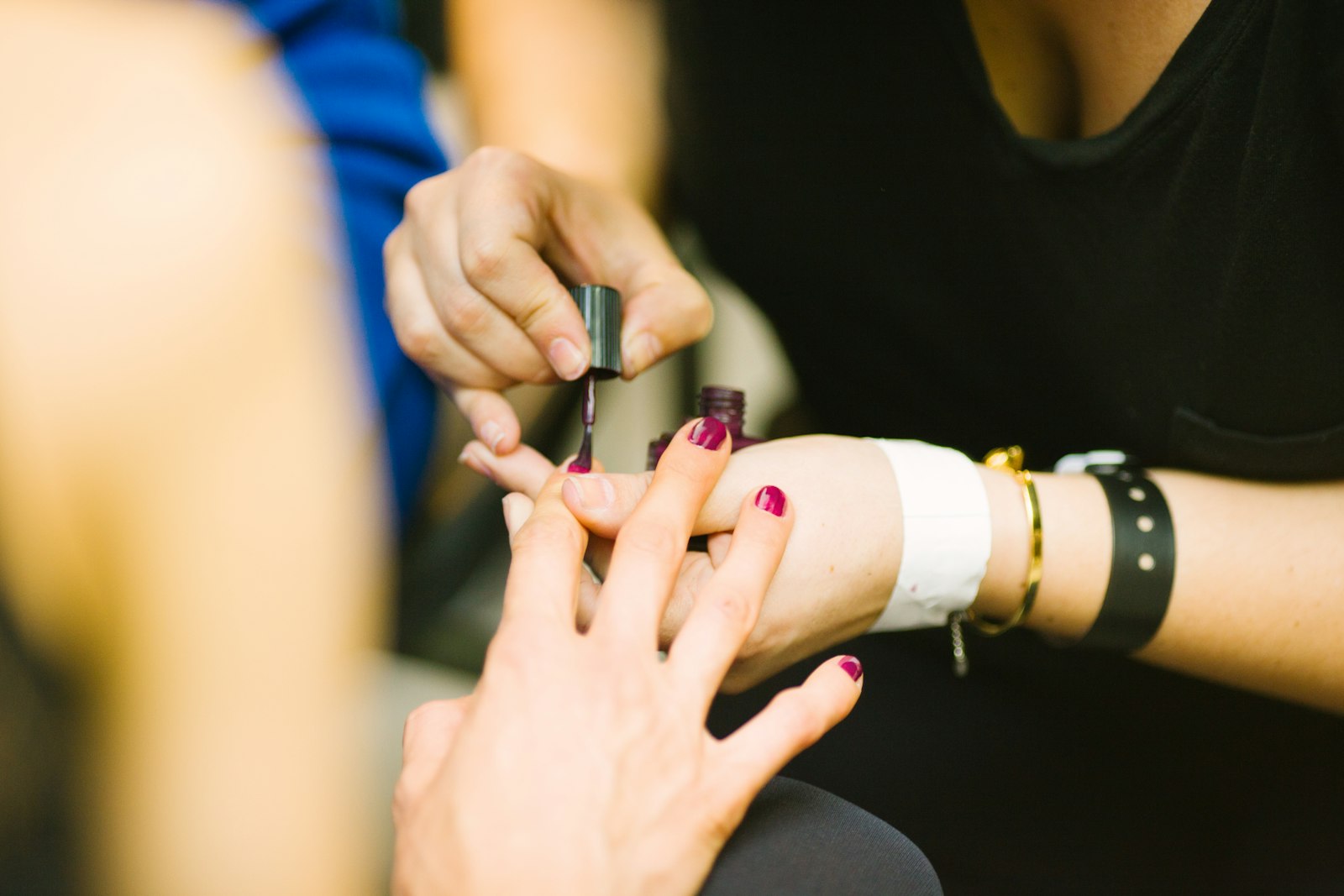 A technician painting a client's nails dark red