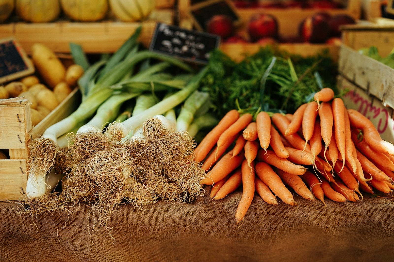 A market stall of carrots and leeks in wooden crates
