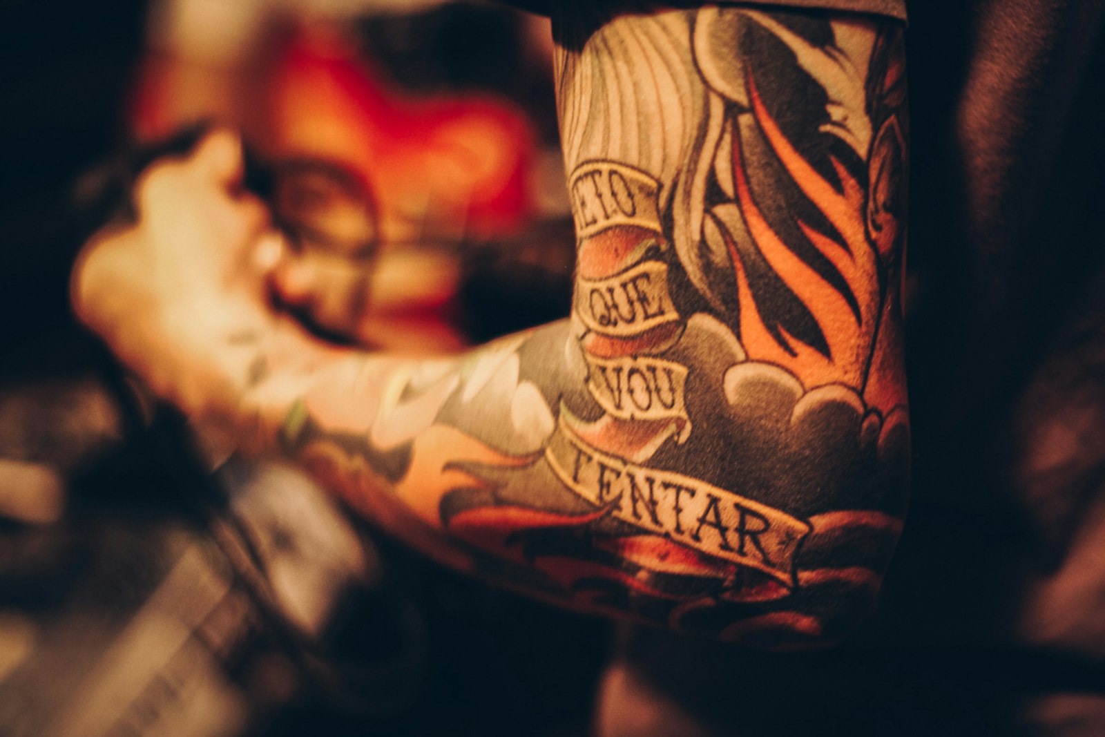 A finished colour tattoo sleeve with flames and a script banner