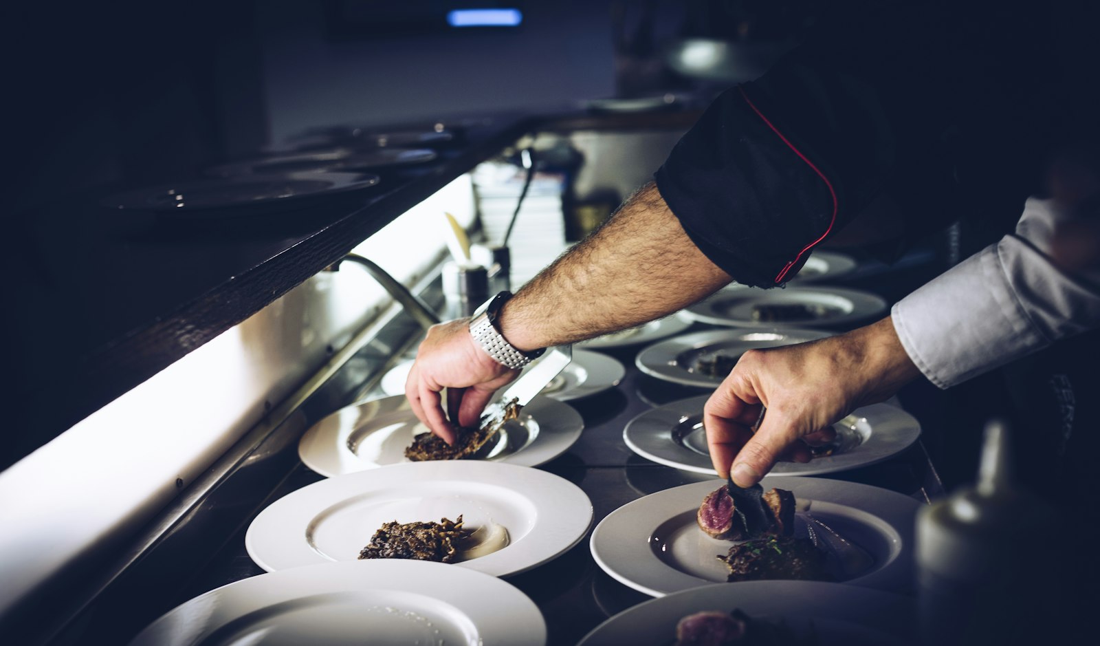 Chefs plating a row of identical dishes