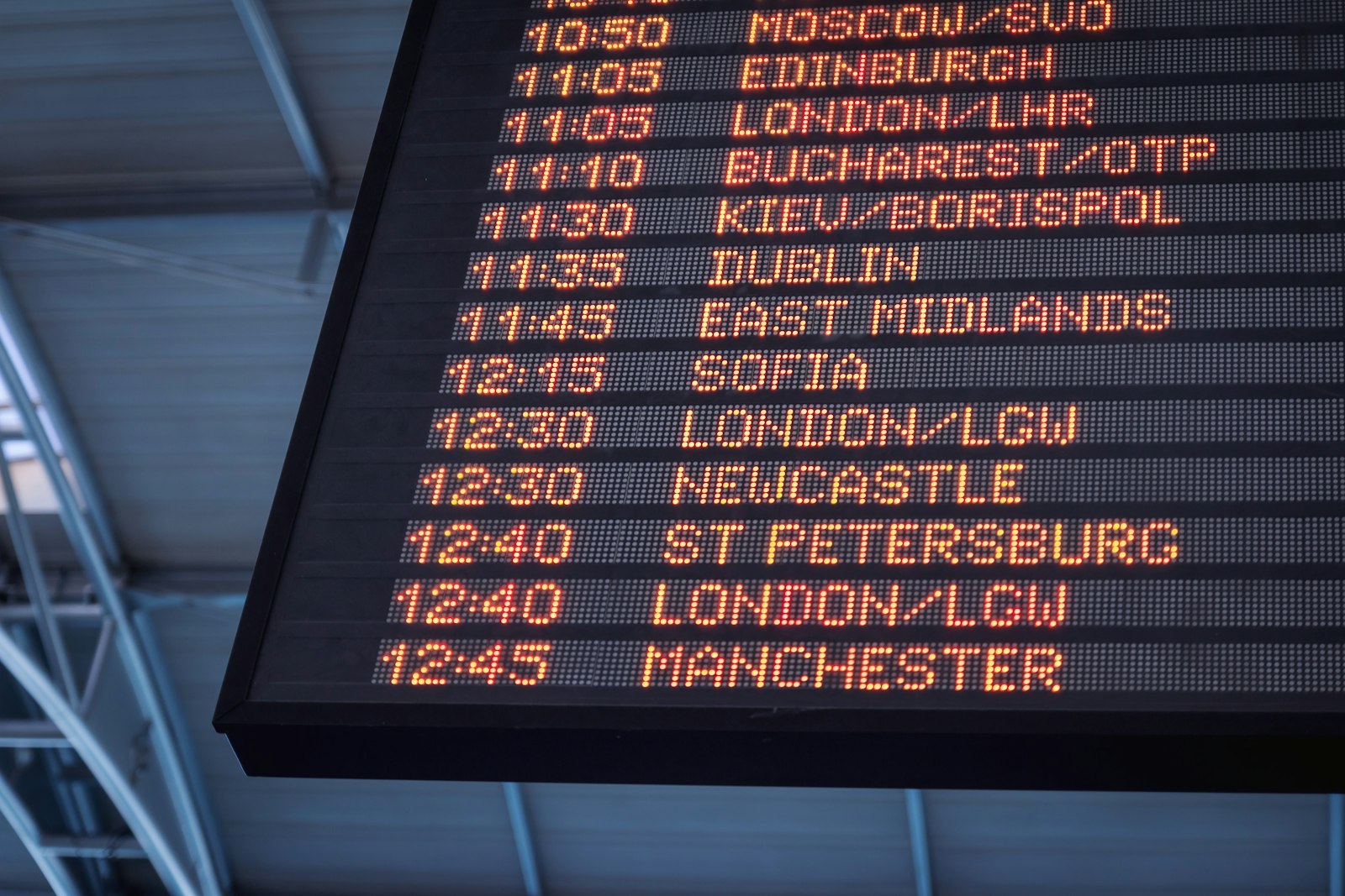 An airport departures board listing UK cities
