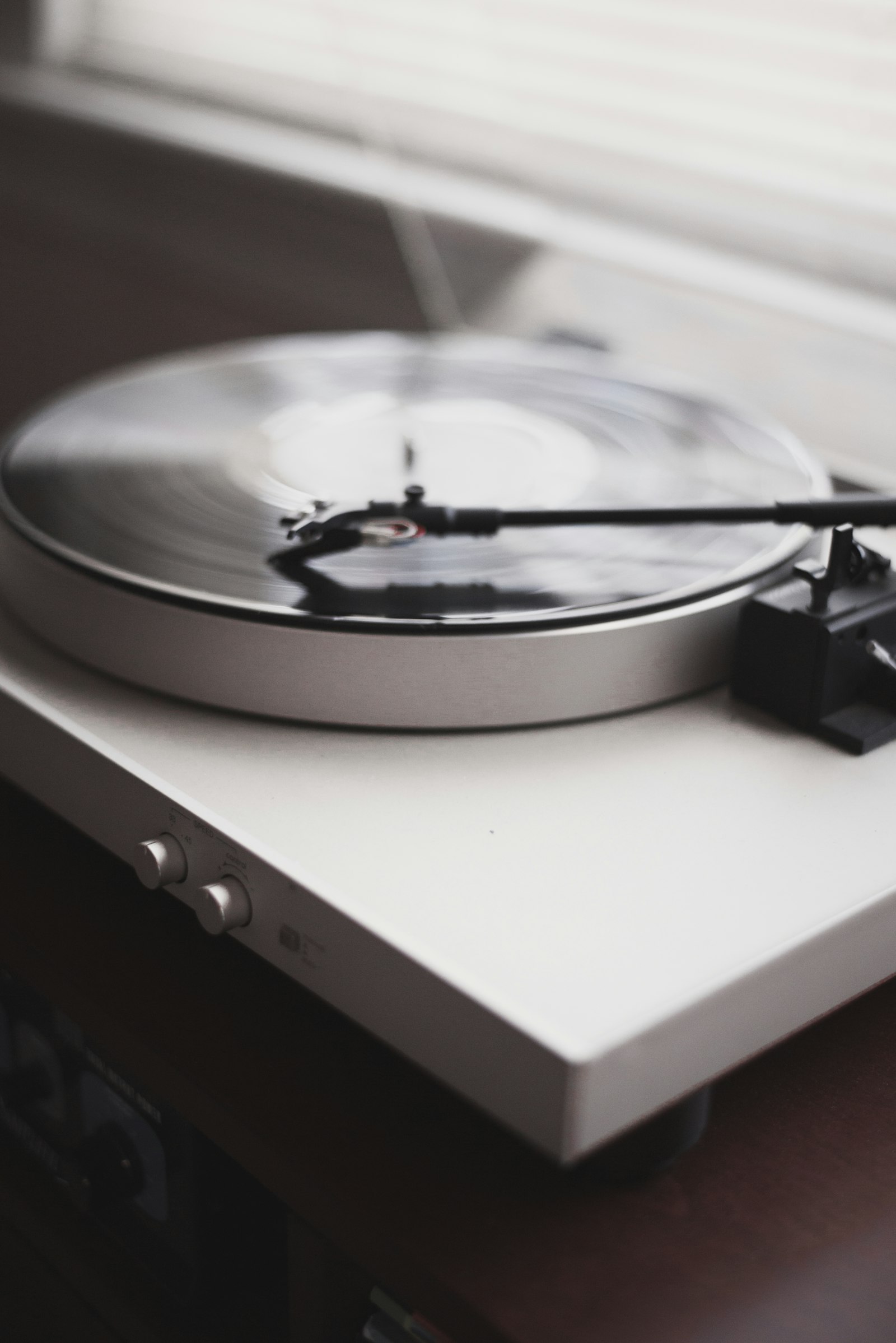 A minimalist white turntable with the tonearm on the record