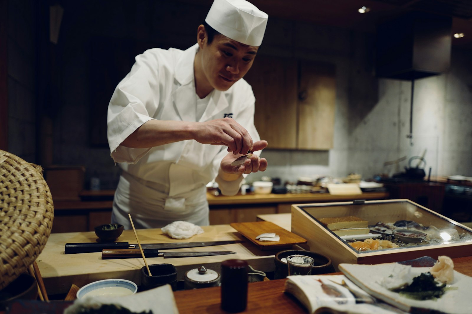 A sushi chef shaping sushi at a wooden counter