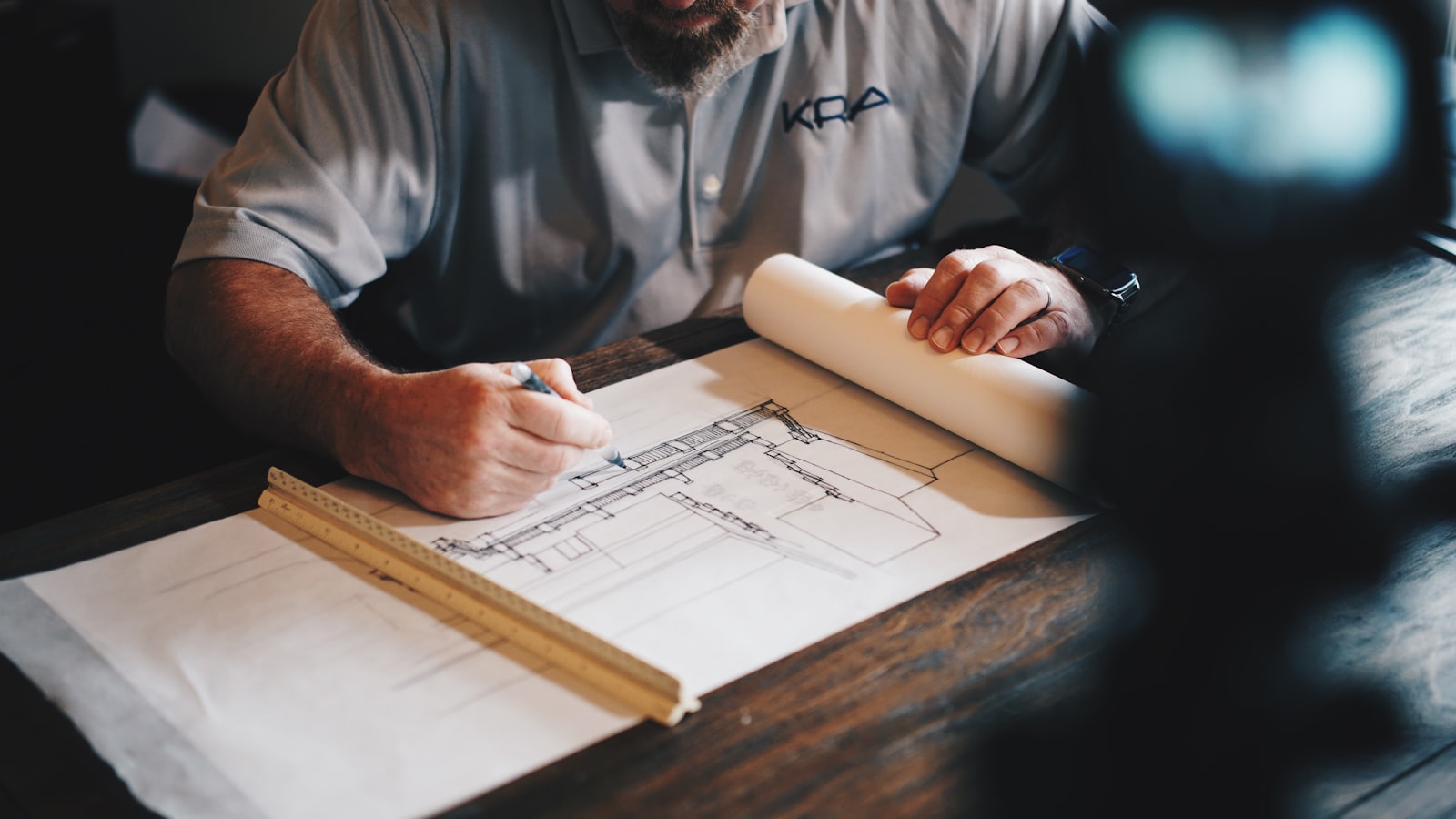 An architect drafting by hand with a pencil and a rule