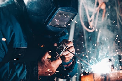 A welder working under a mask, sparks flying