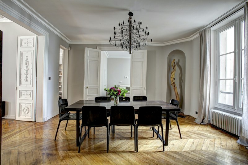 A dining room with tall panelled doors and a wire chandelier