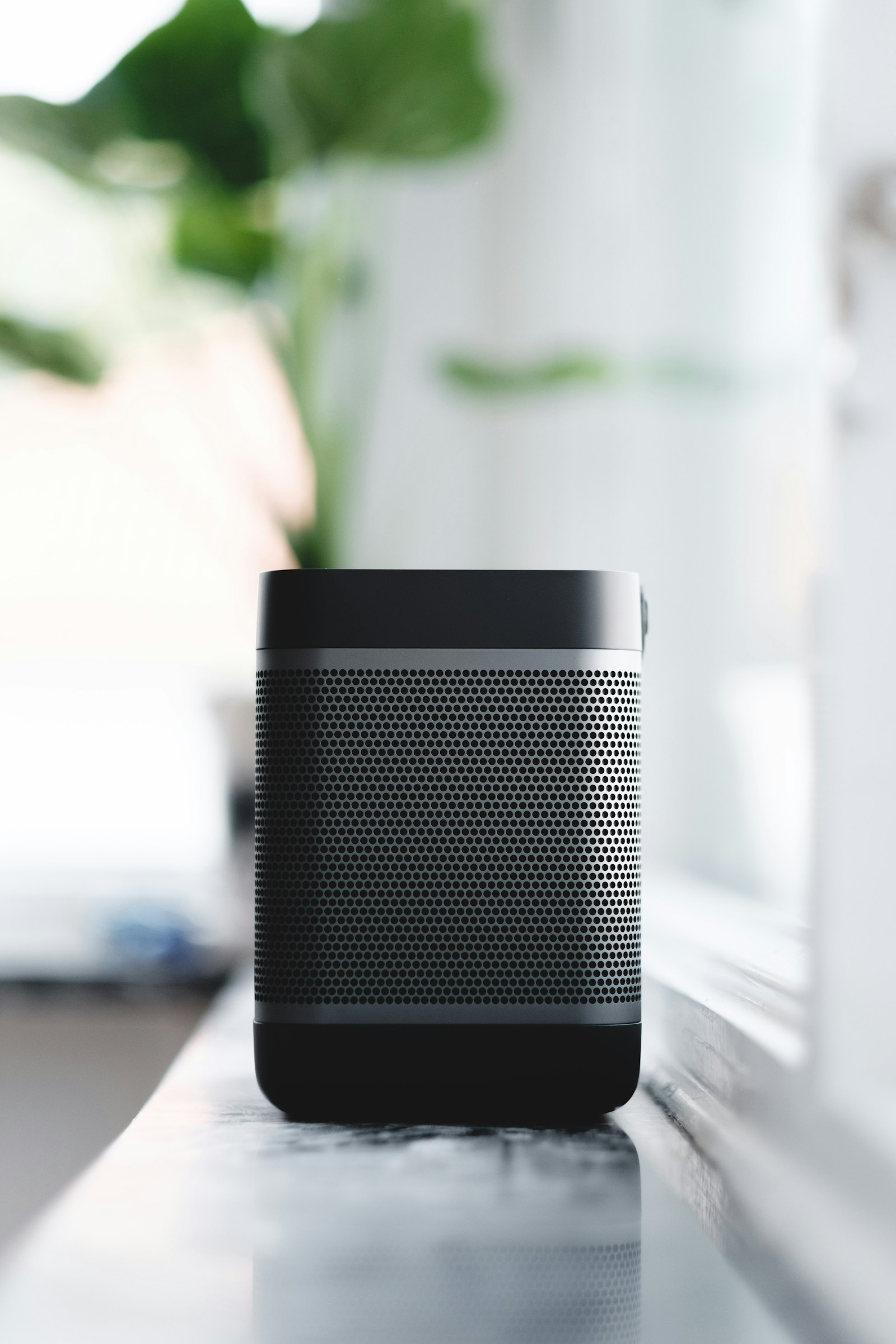 A compact mesh speaker on a windowsill