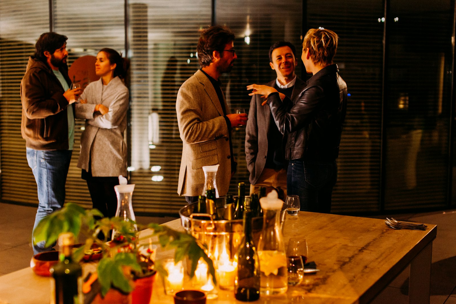 A small group with drinks around a candlelit table