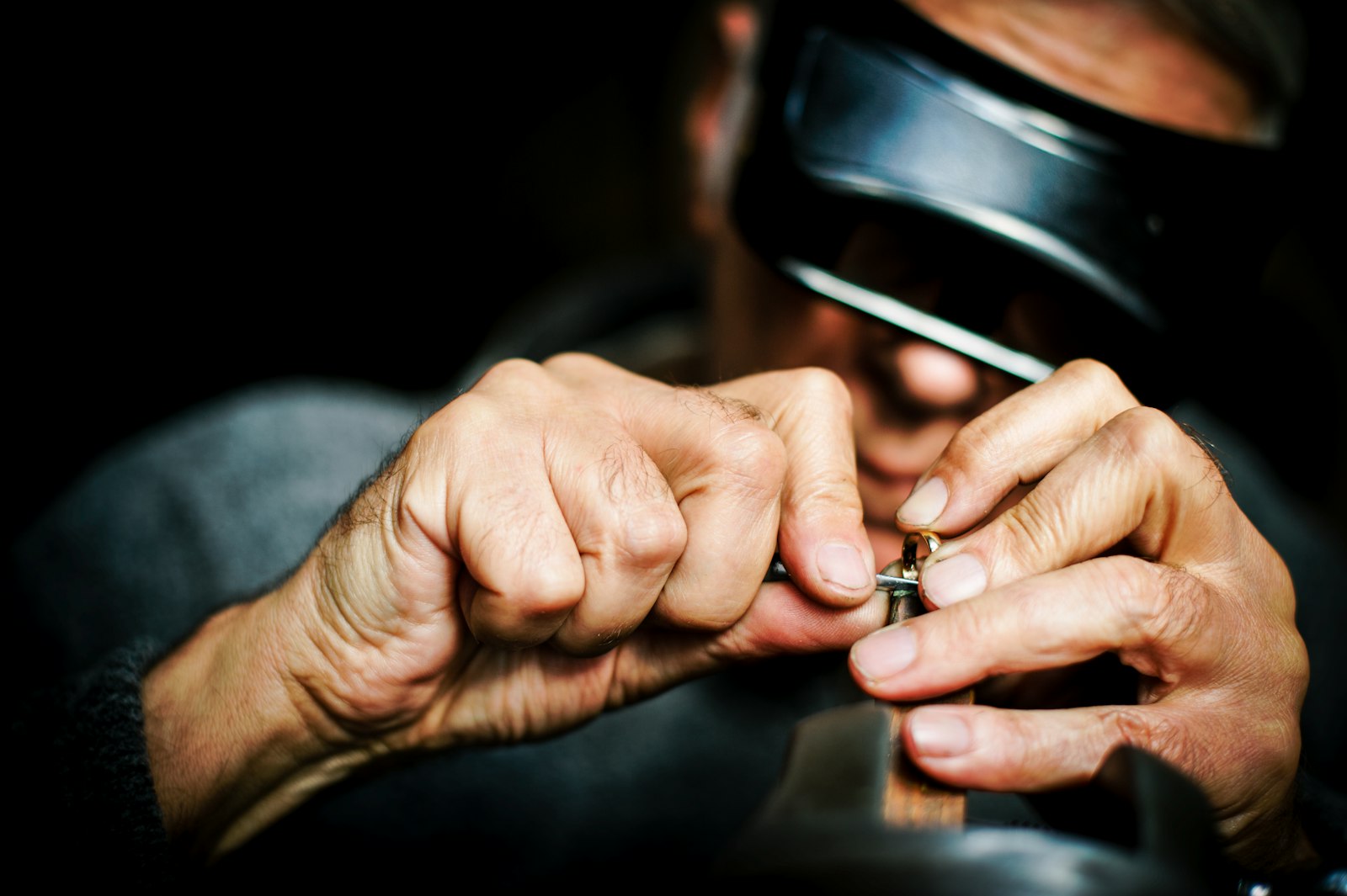 Hands holding a ring with a loupe visor blurred behind