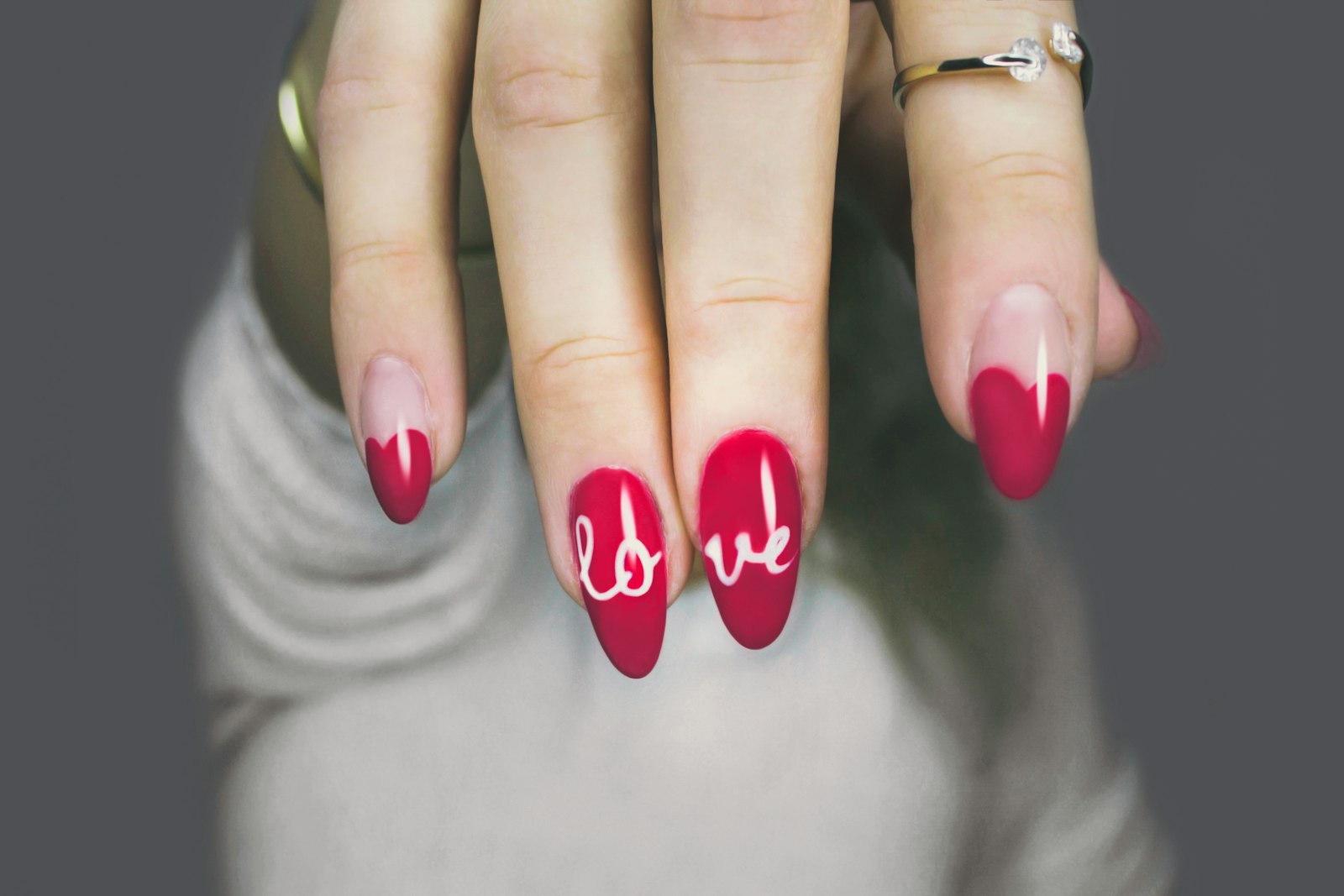 Long red almond nails with a small white script detail