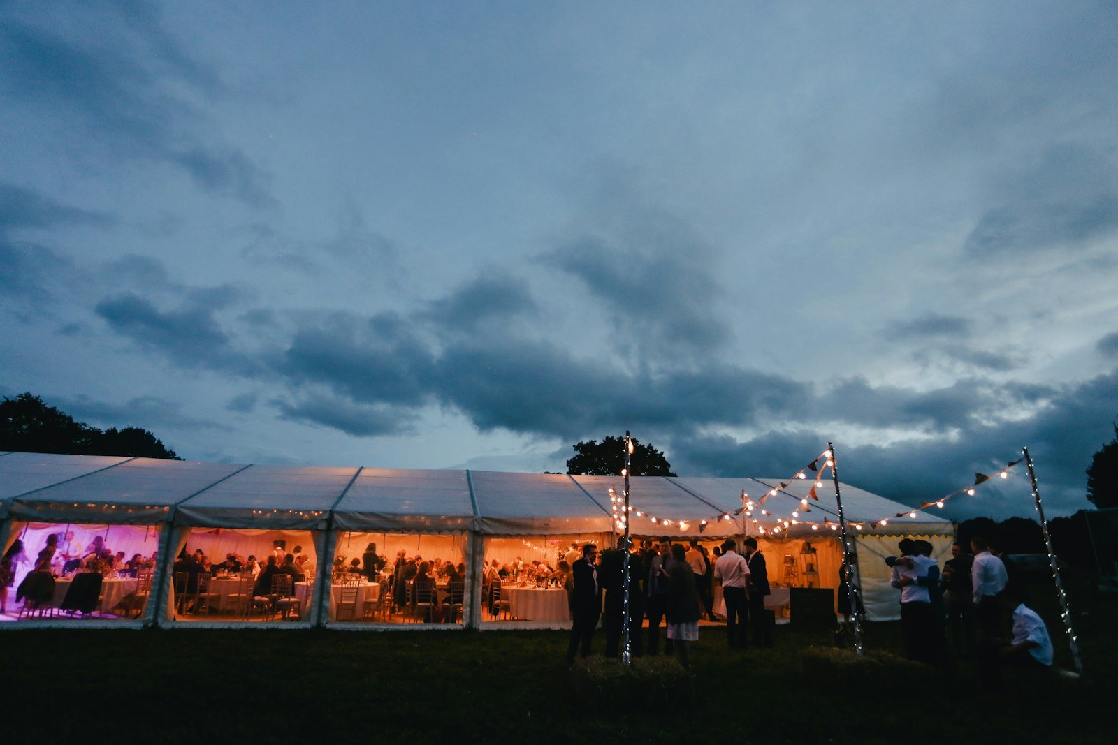 A marquee glowing at dusk with festoon lights