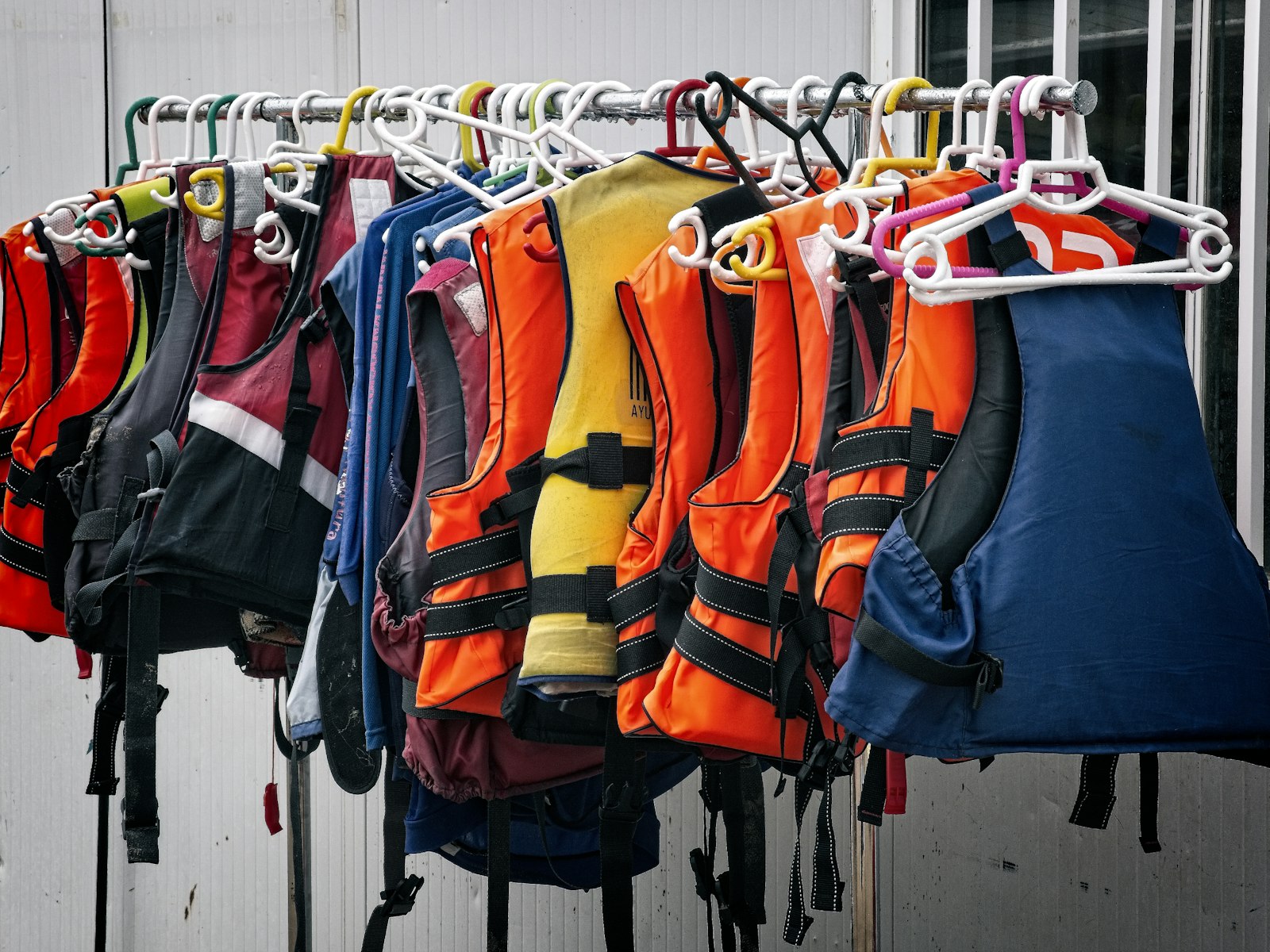 Life jackets in assorted colours hanging on a rail