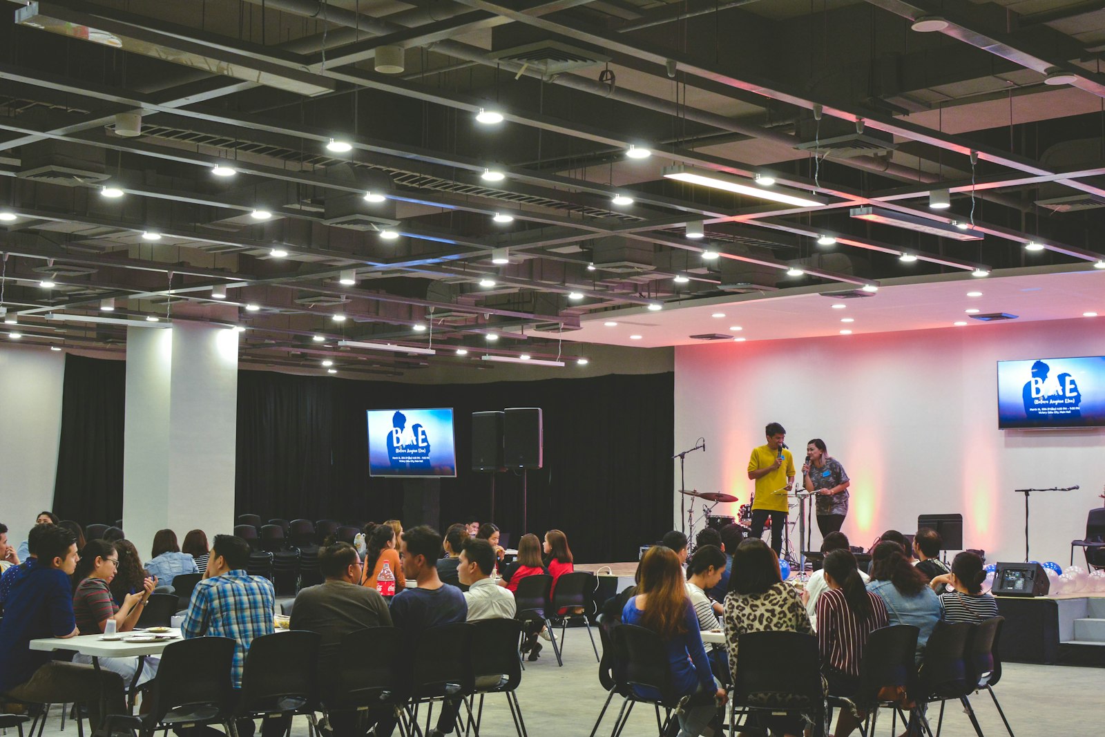 Attendees at tables facing a stage