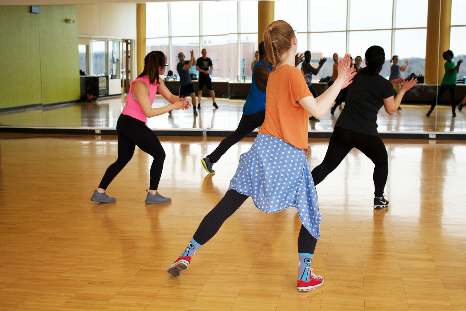 An adult class in a mirrored studio, backs to the mirror