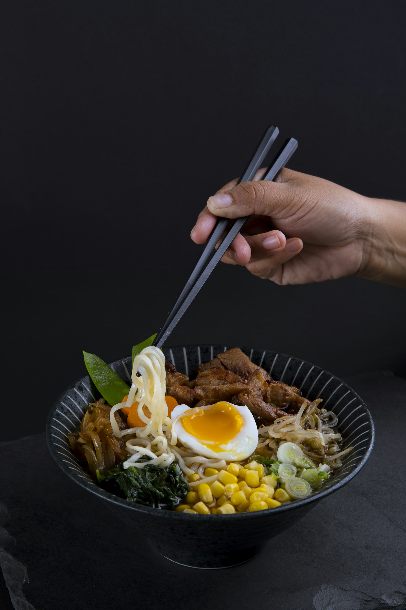 Chopsticks lifting noodles over a bowl
