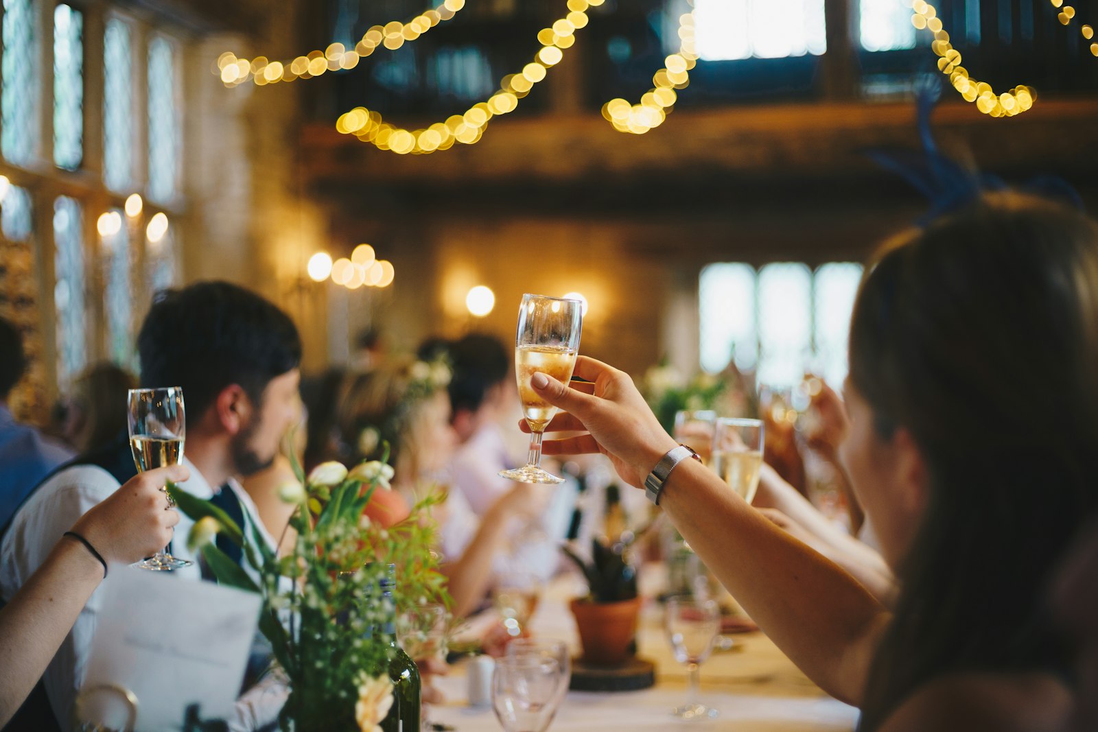 Guests toasting with champagne under festoon lights