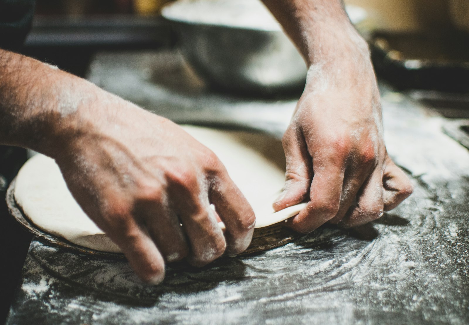 Hands stretching a pizza base