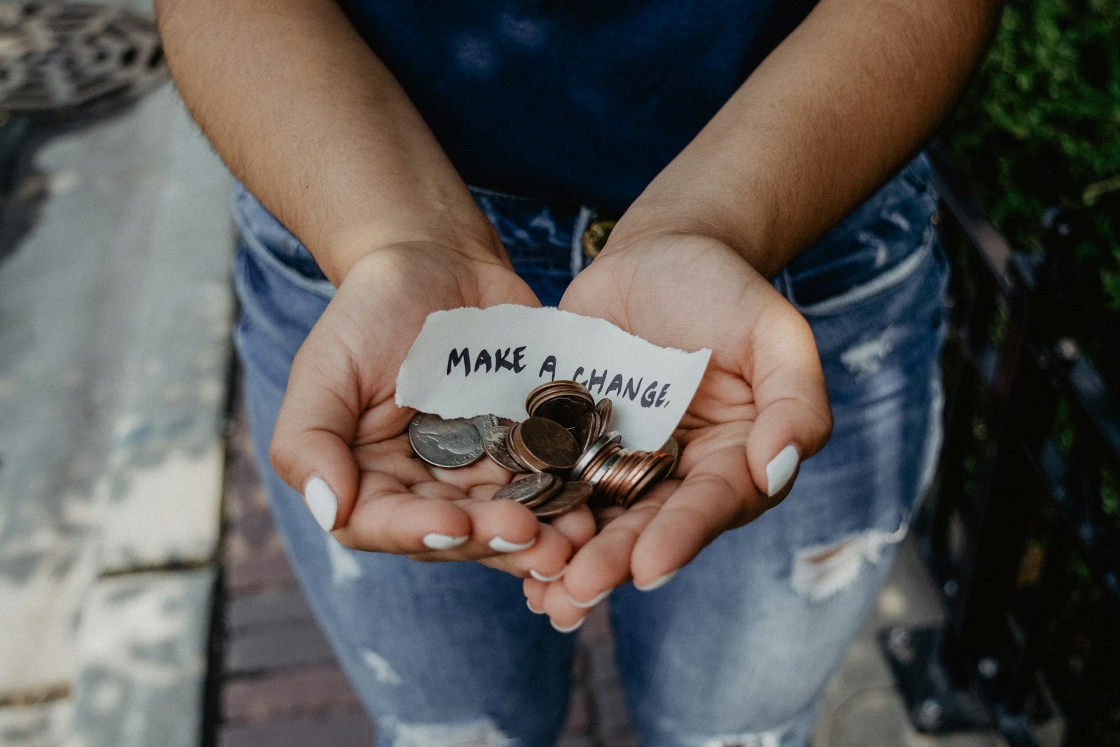 Cupped hands holding coins and a note