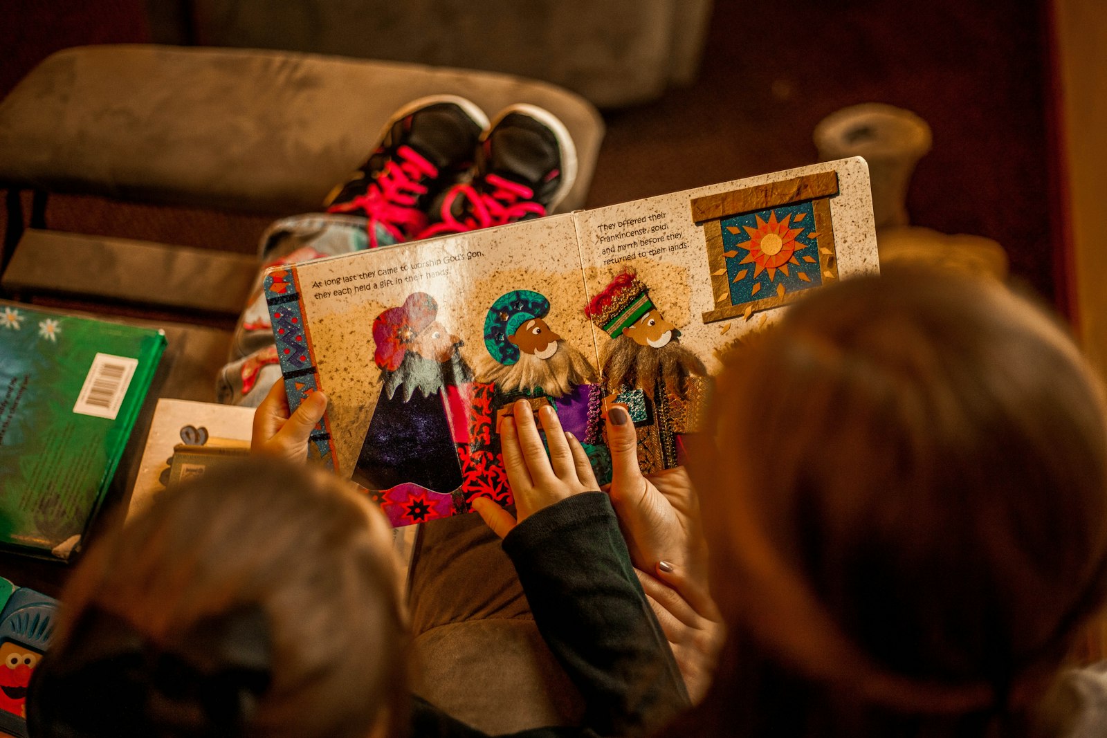 Two children reading a picture book together on a sofa