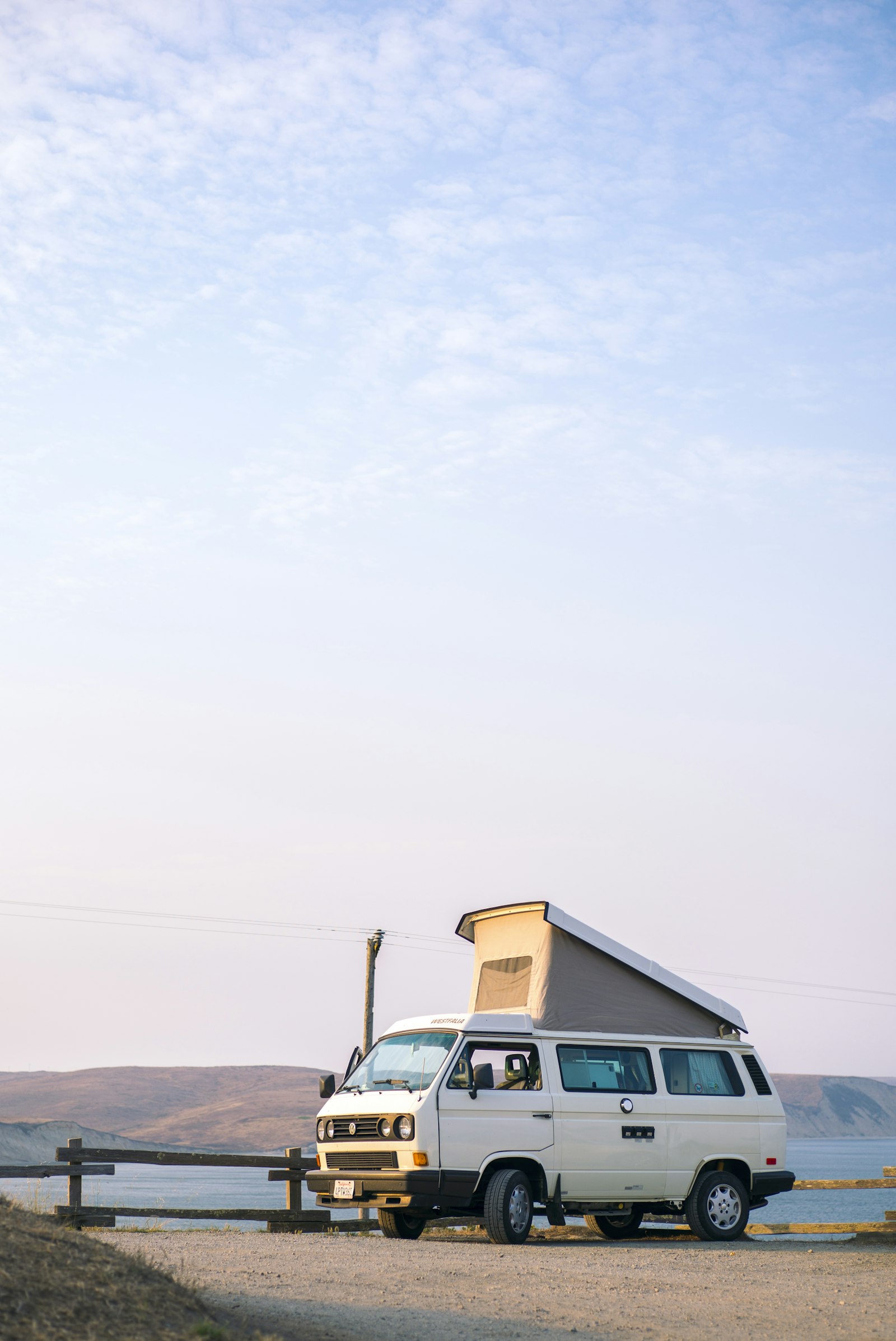 A pop-top camper parked on a pale shoreline