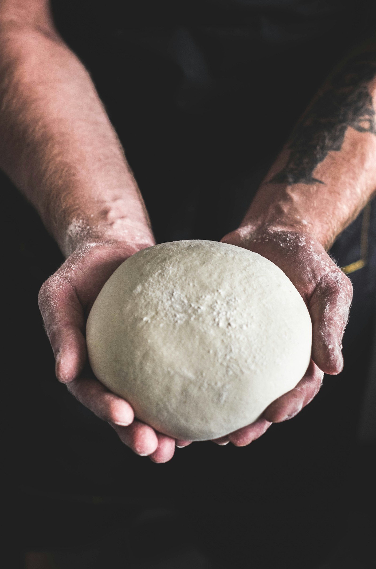 Floured hands holding a ball of dough