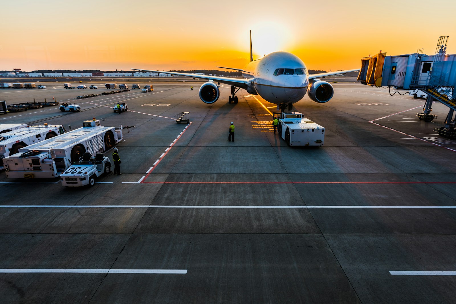 An airliner at a jet bridge at sunrise