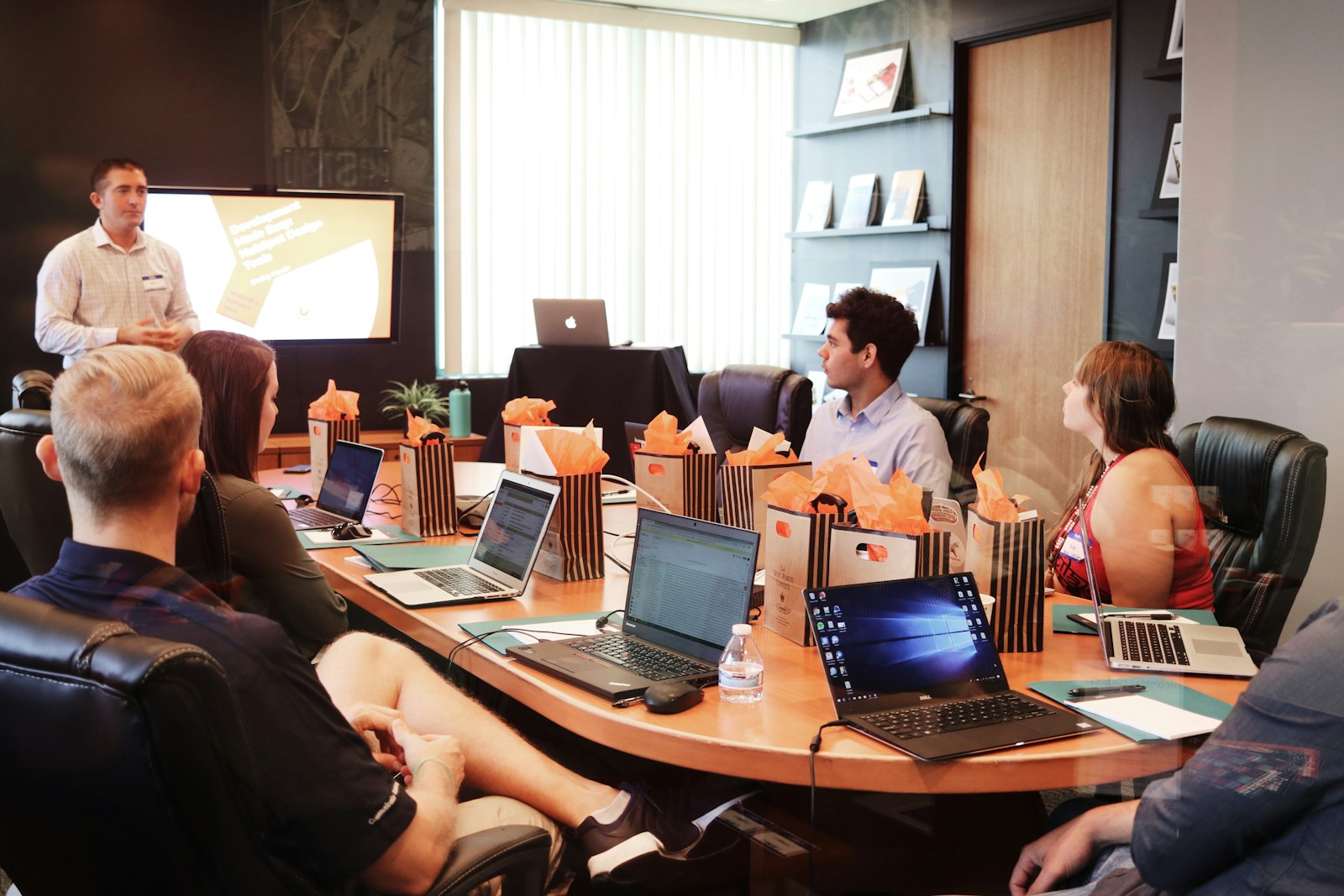 A man presenting to people seated at a table with laptops