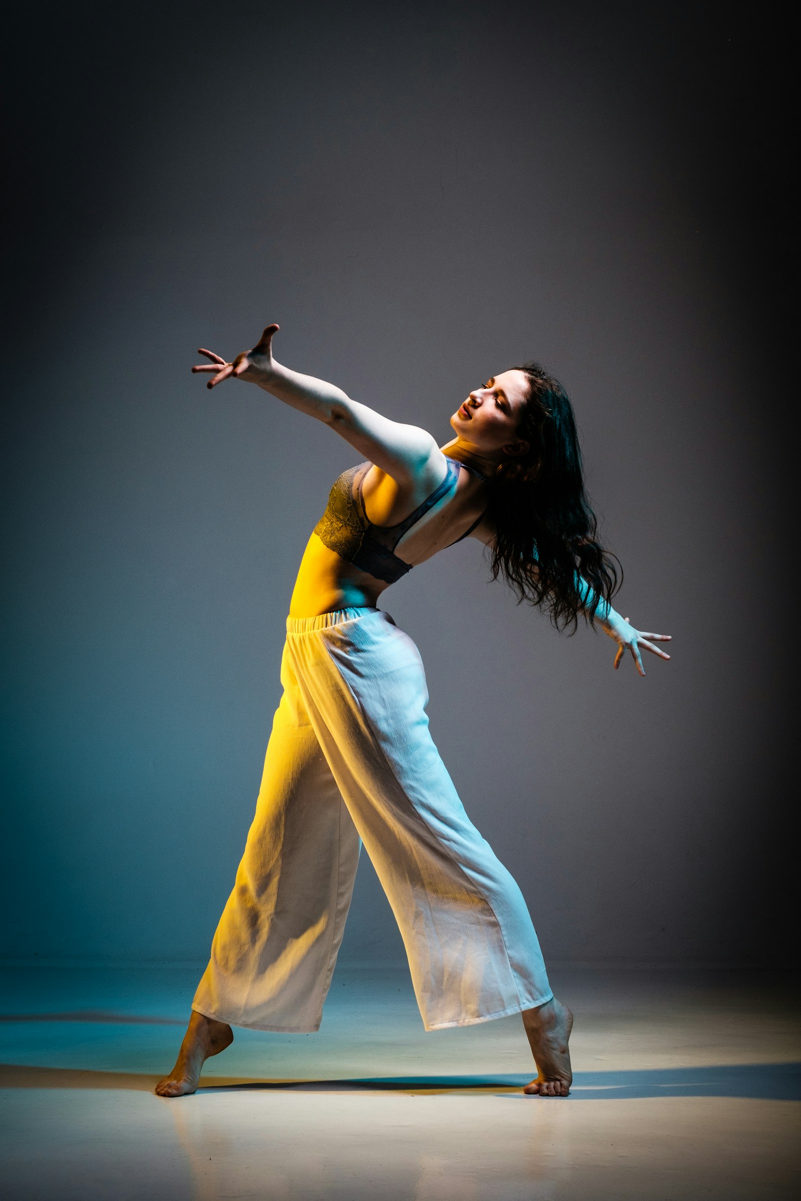 A dancer in yellow trousers mid-move under coloured stage light