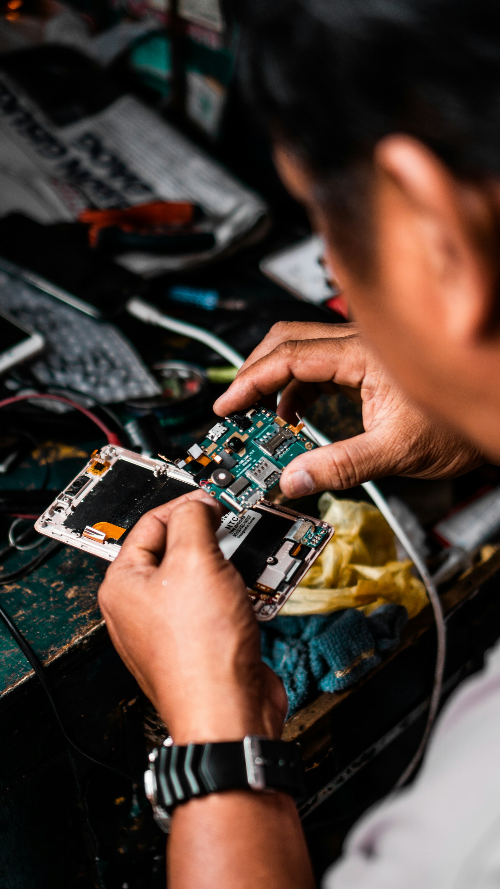 A technician lifting a logic board out of an open phone