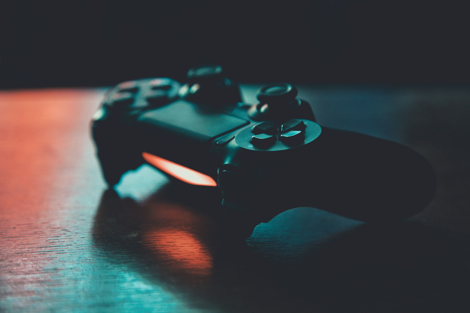 A controller on a dark surface with teal and orange rim light