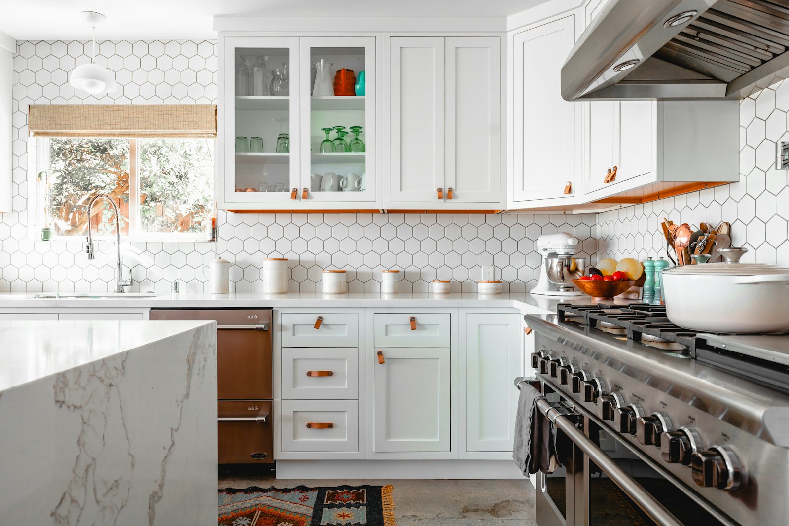 A bright white kitchen with hexagonal wall tiles and a marble island, cleaned