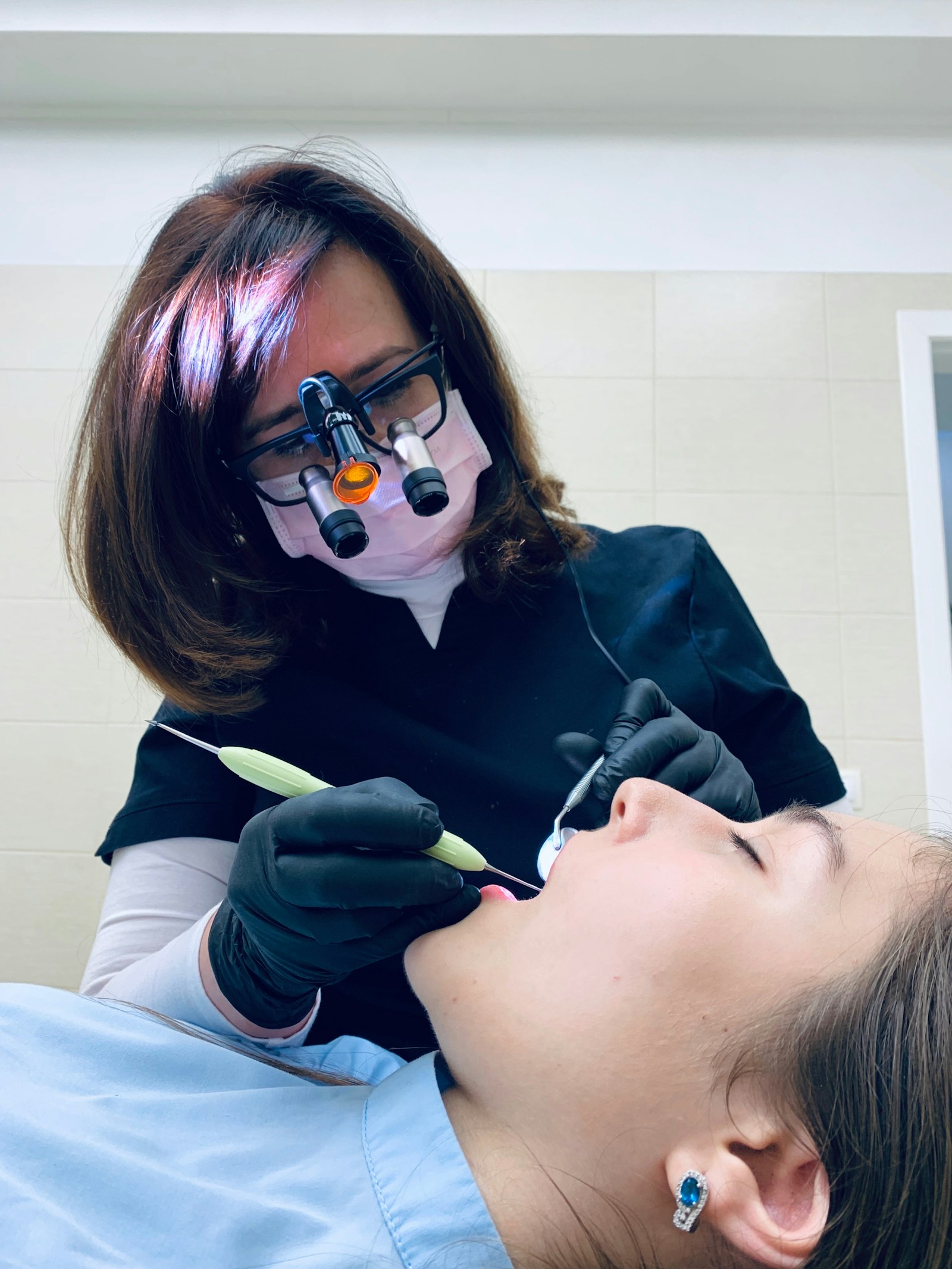 A hygienist holding a tool at a patient's mouth