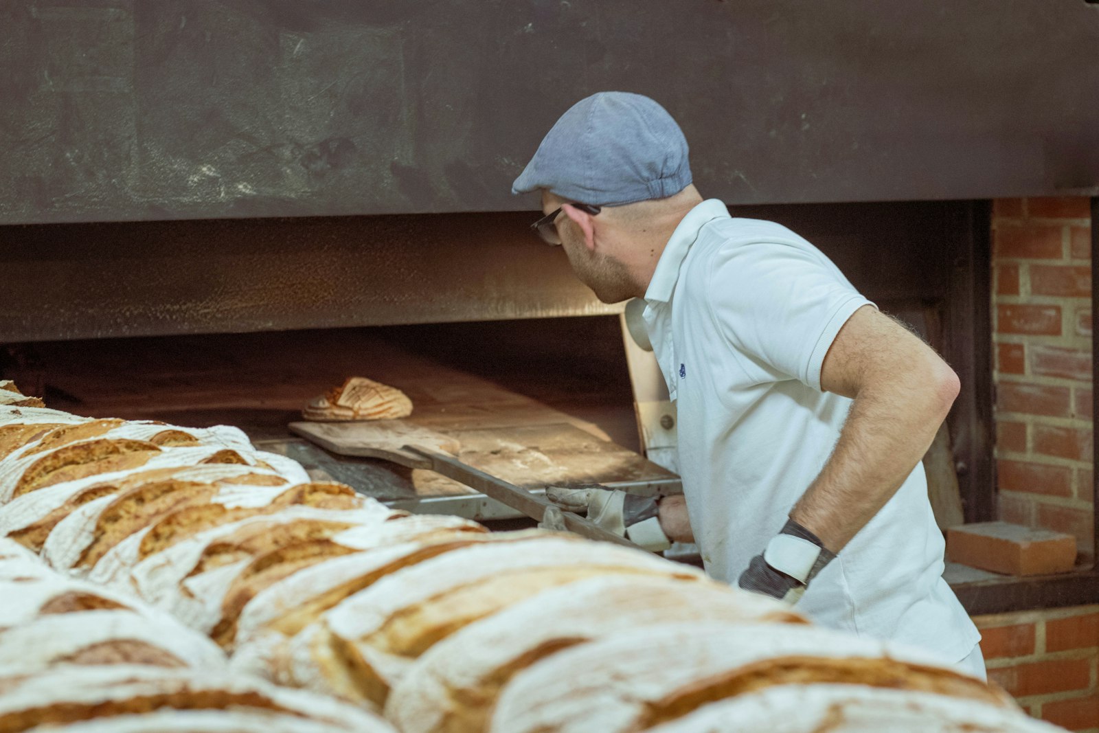 A baker loading a brick oven with a long peel