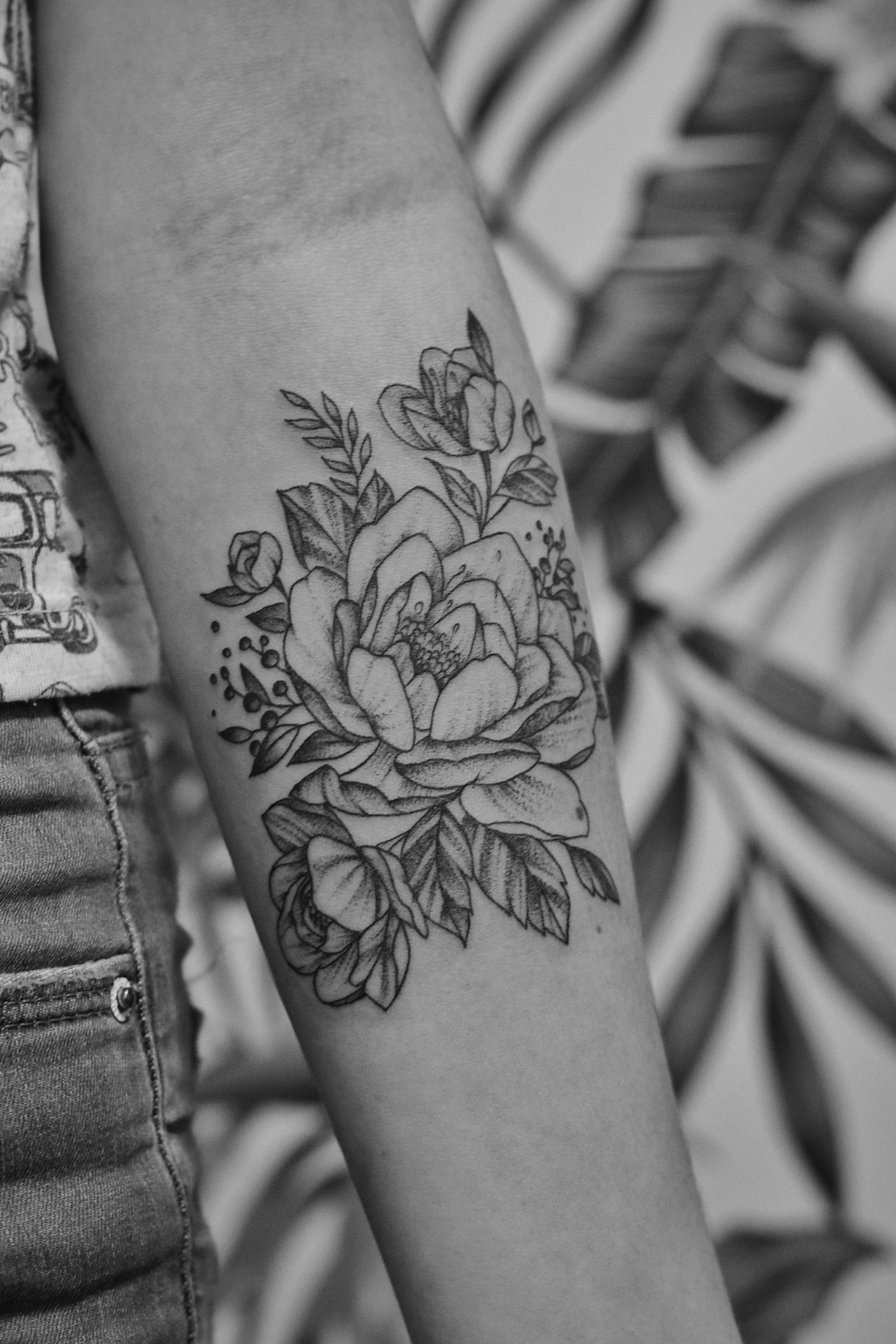 A healed floral forearm tattoo, grayscale