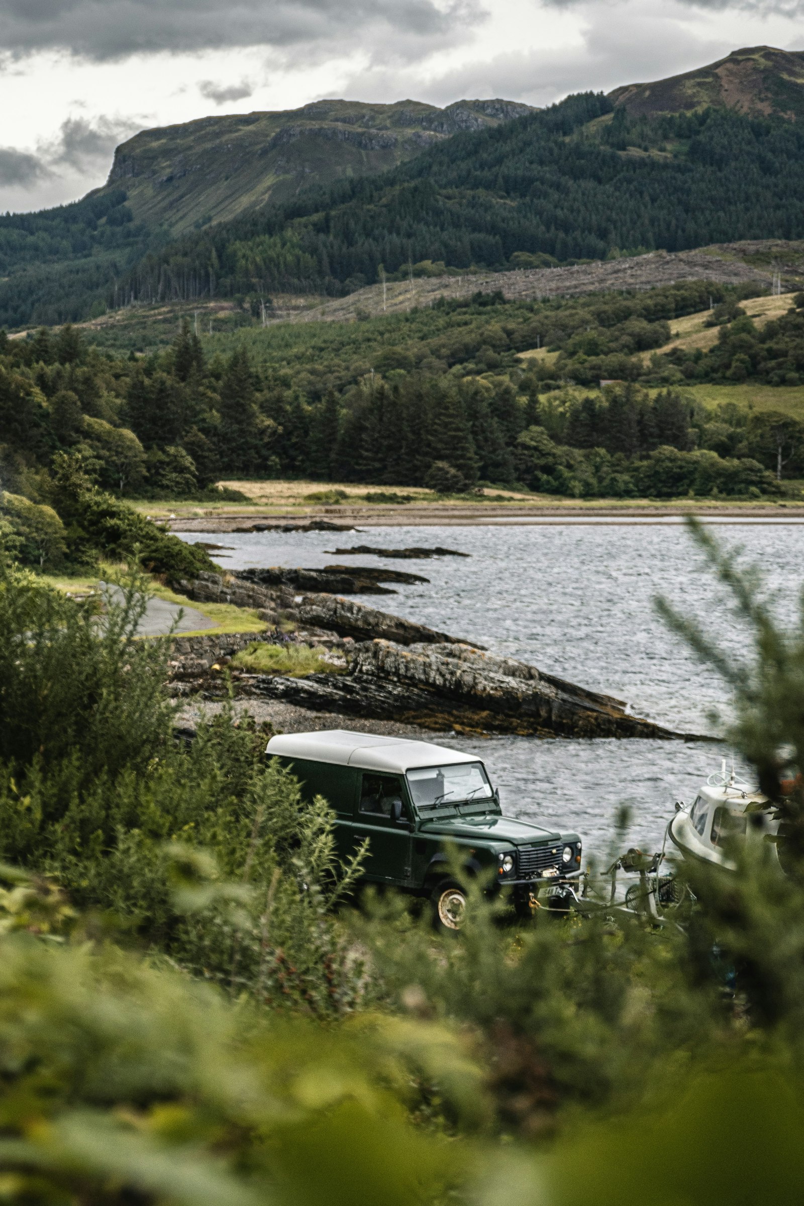 A Defender among bracken above a loch