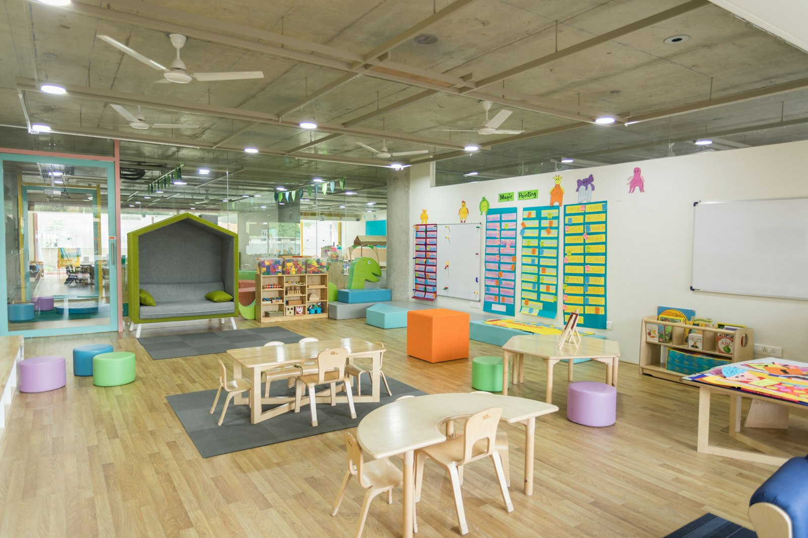 A bright nursery playroom with low tables and a reading nook