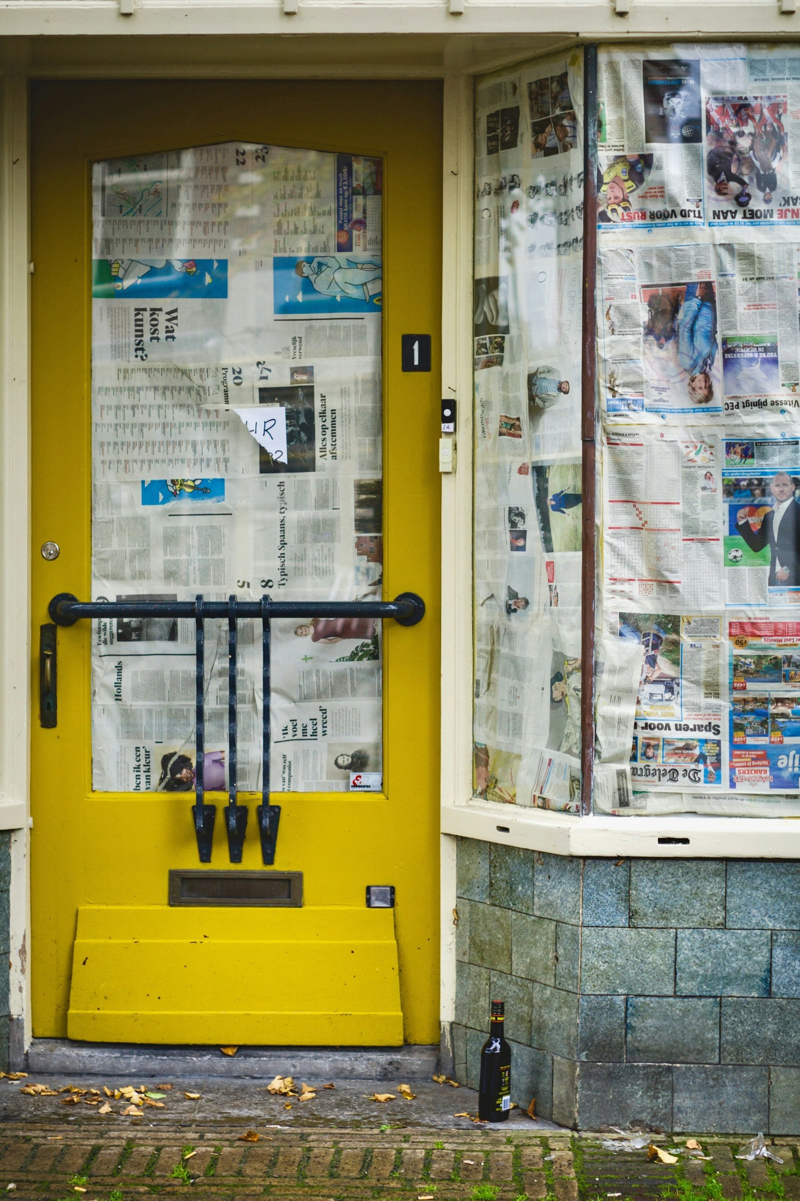 A yellow shop door and its windows papered over with newspaper, a few weeks before opening