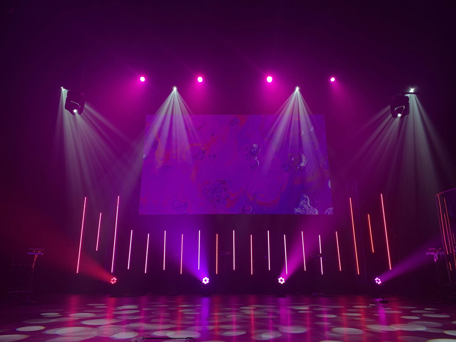 An empty stage lit in pink and purple