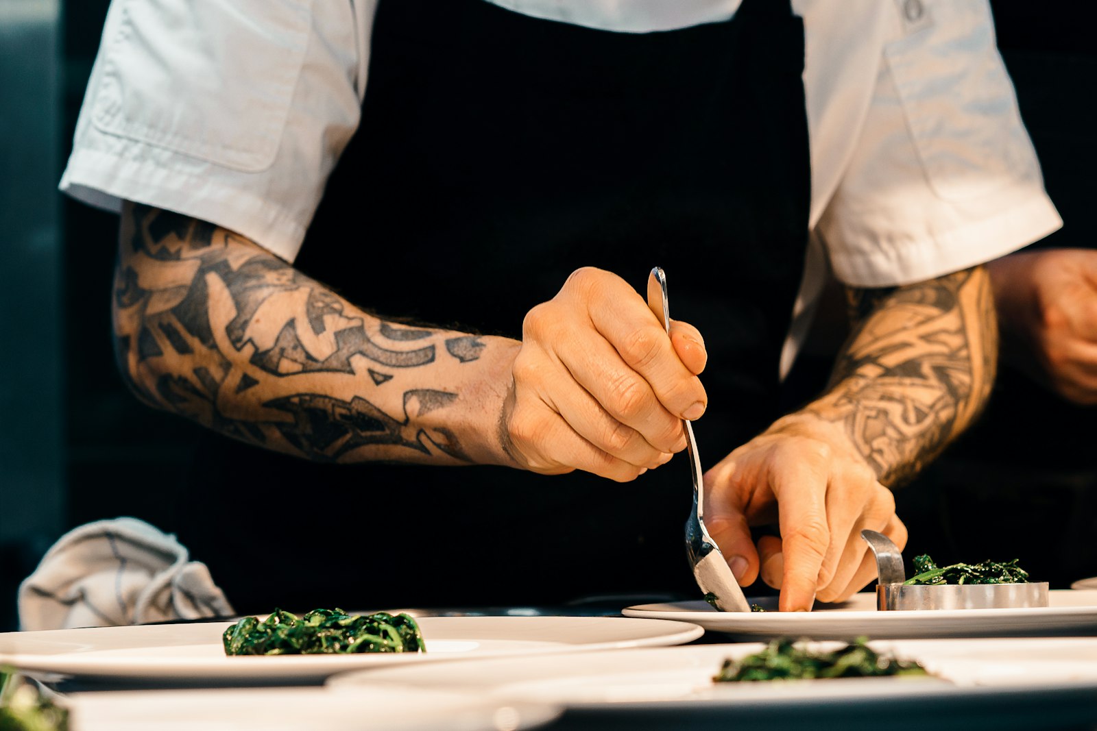 A chef finishing plates at the pass