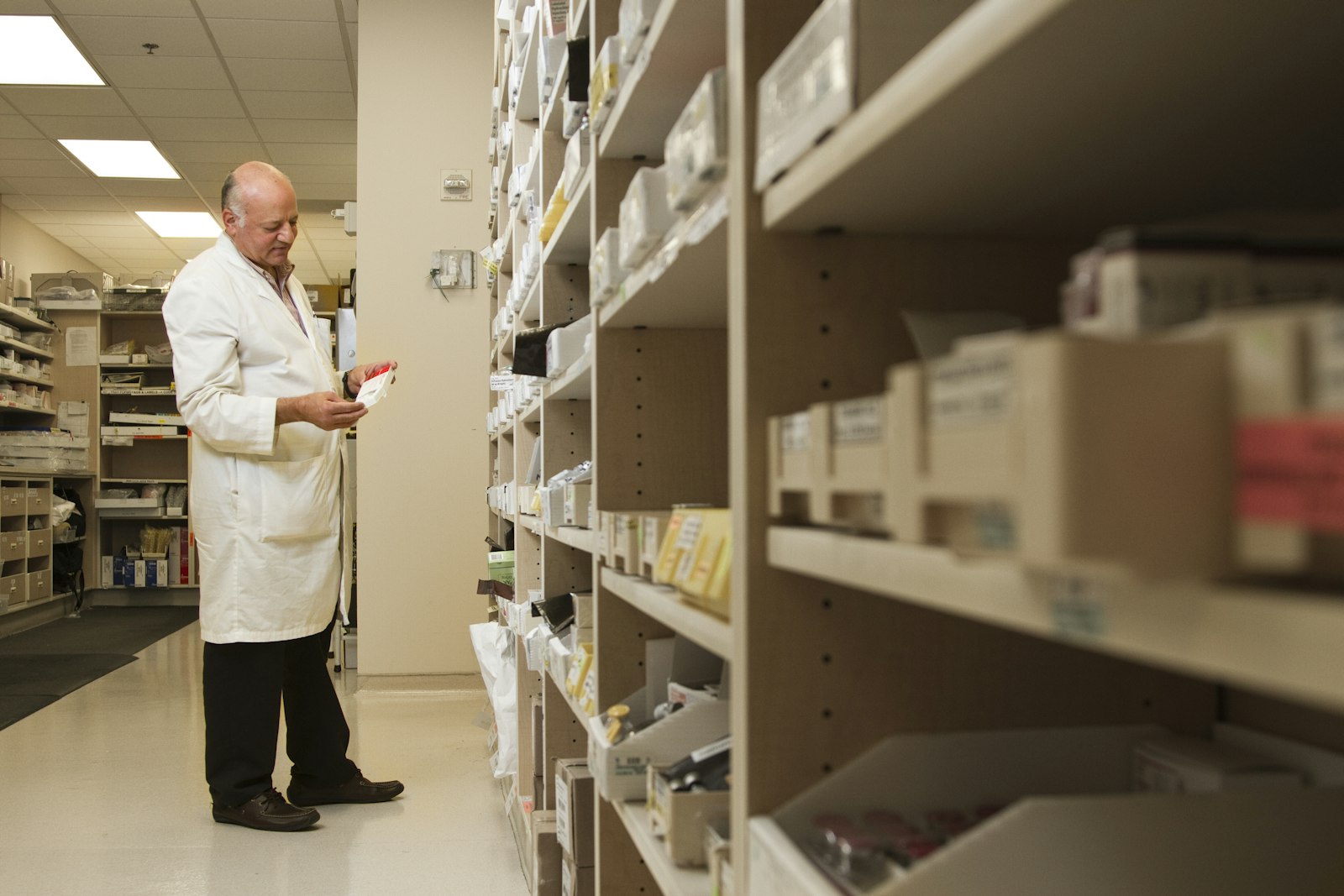 A pharmacist standing by a wooden medicine shelf