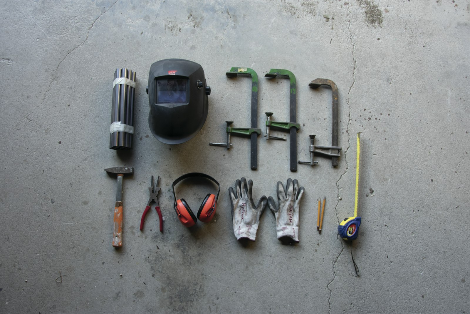 Work gloves, ear defenders, clamps and a tape measure on concrete
