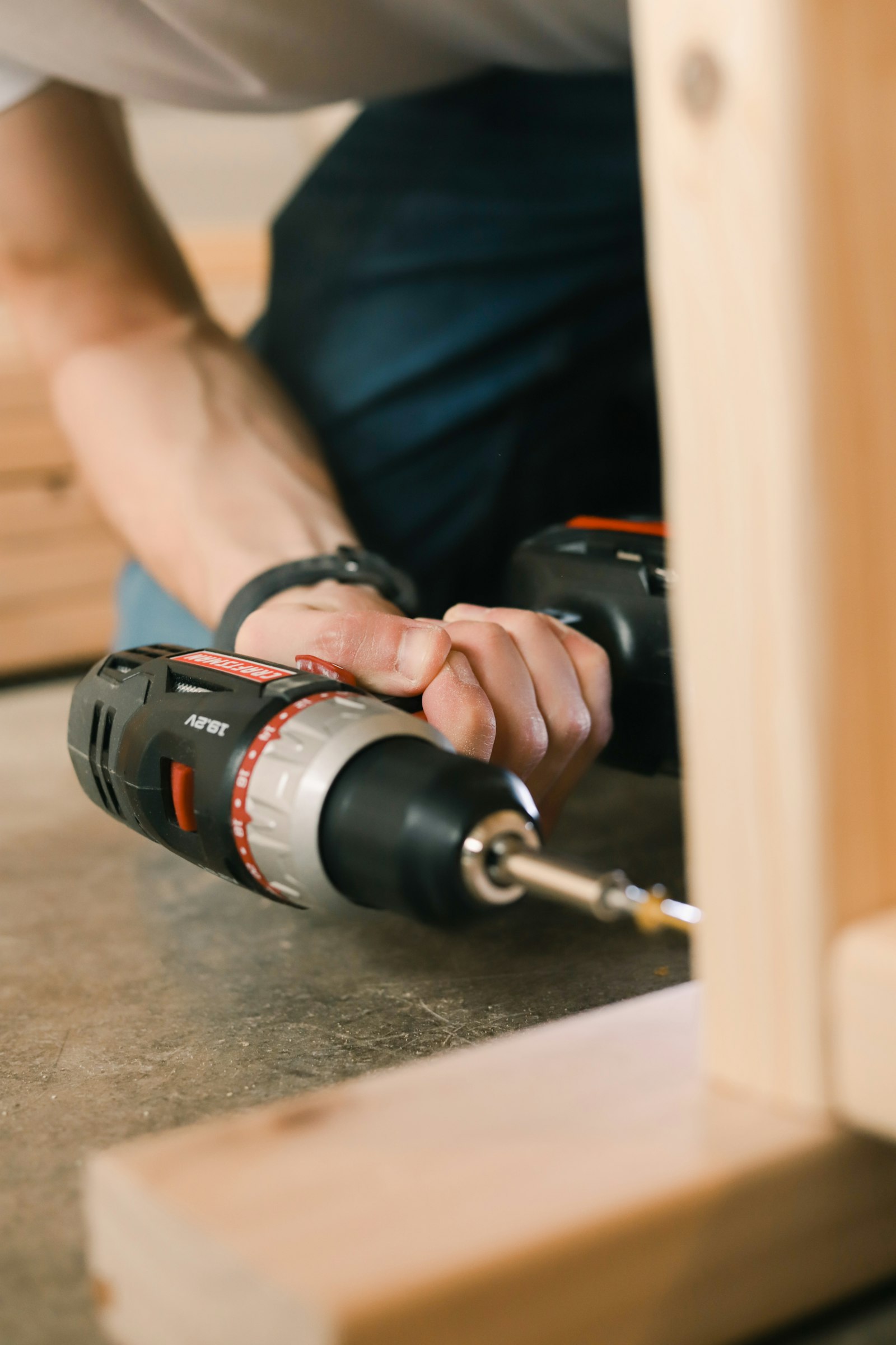 Hands driving a screw into timber with a cordless drill