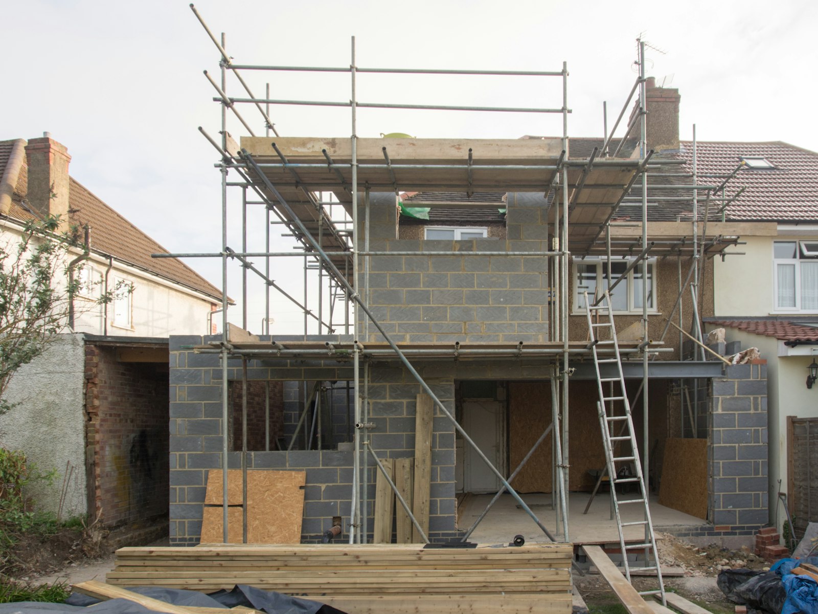 A two-storey block-work extension wrapped in scaffolding