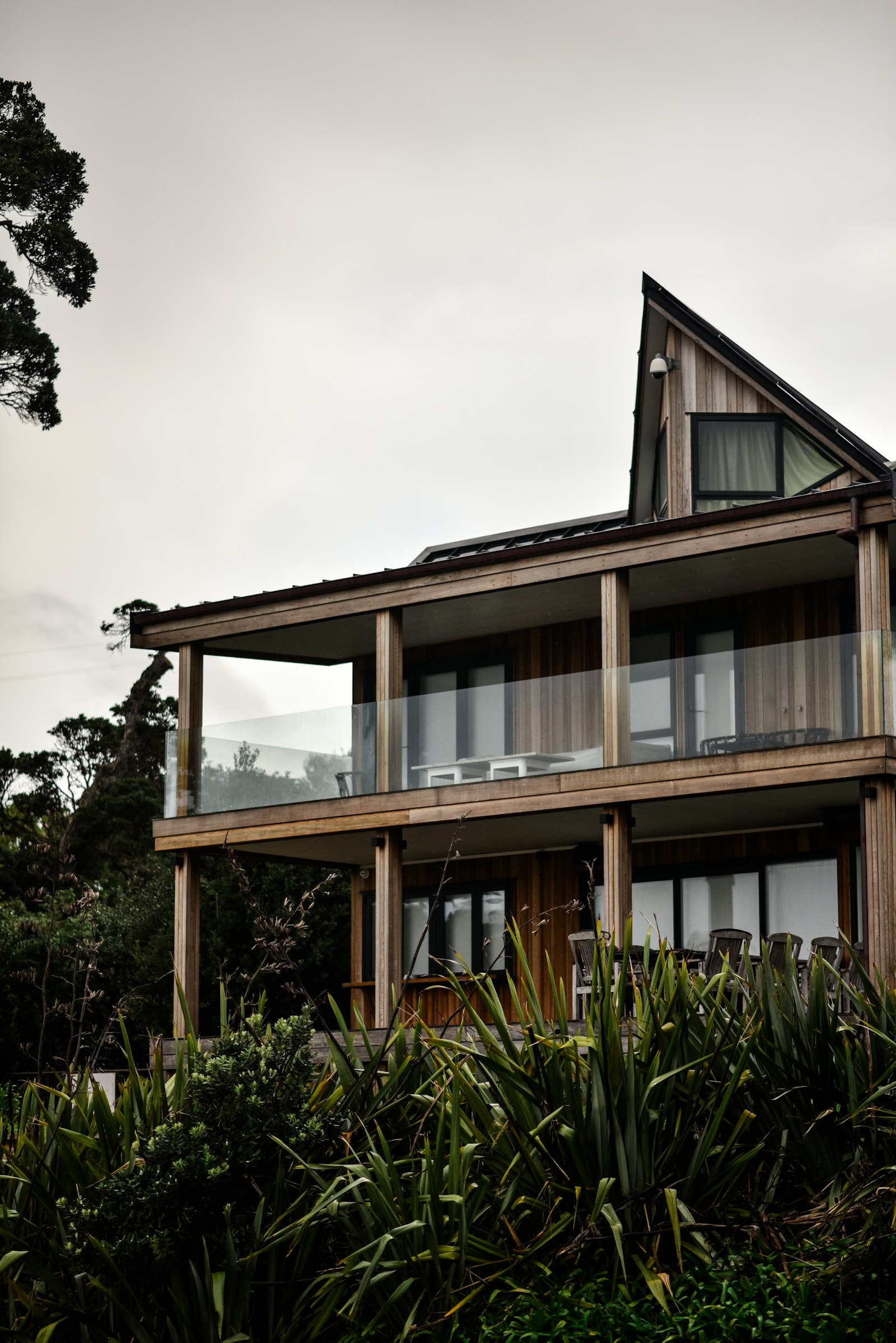 A timber-clad house with stacked balconies behind planting