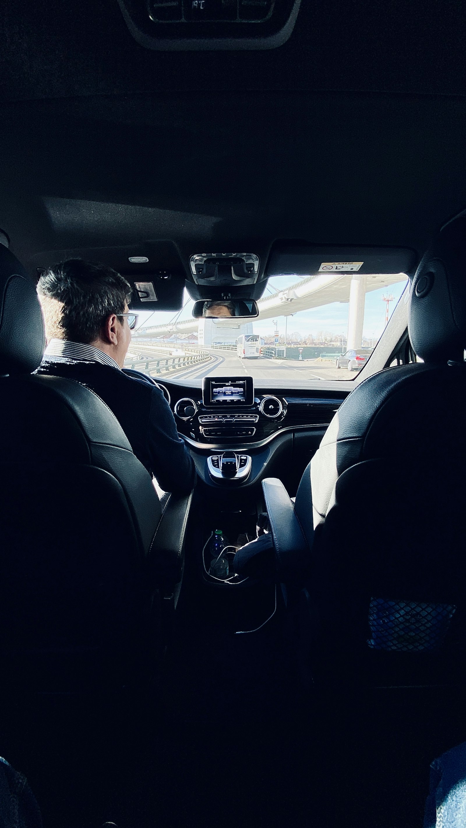 A suited chauffeur driving, seen from the back seat