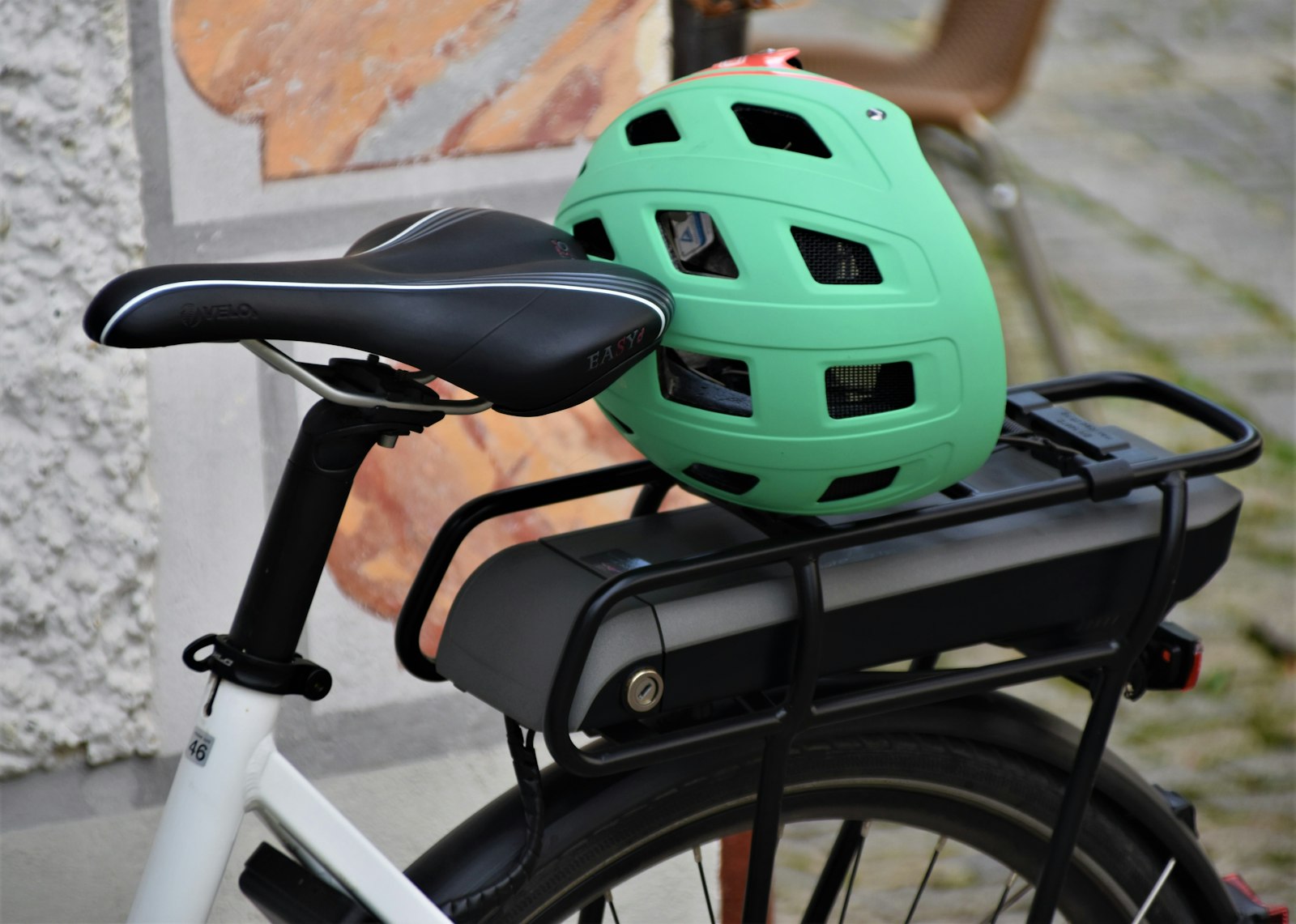An e-bike battery and rack with a helmet resting on it