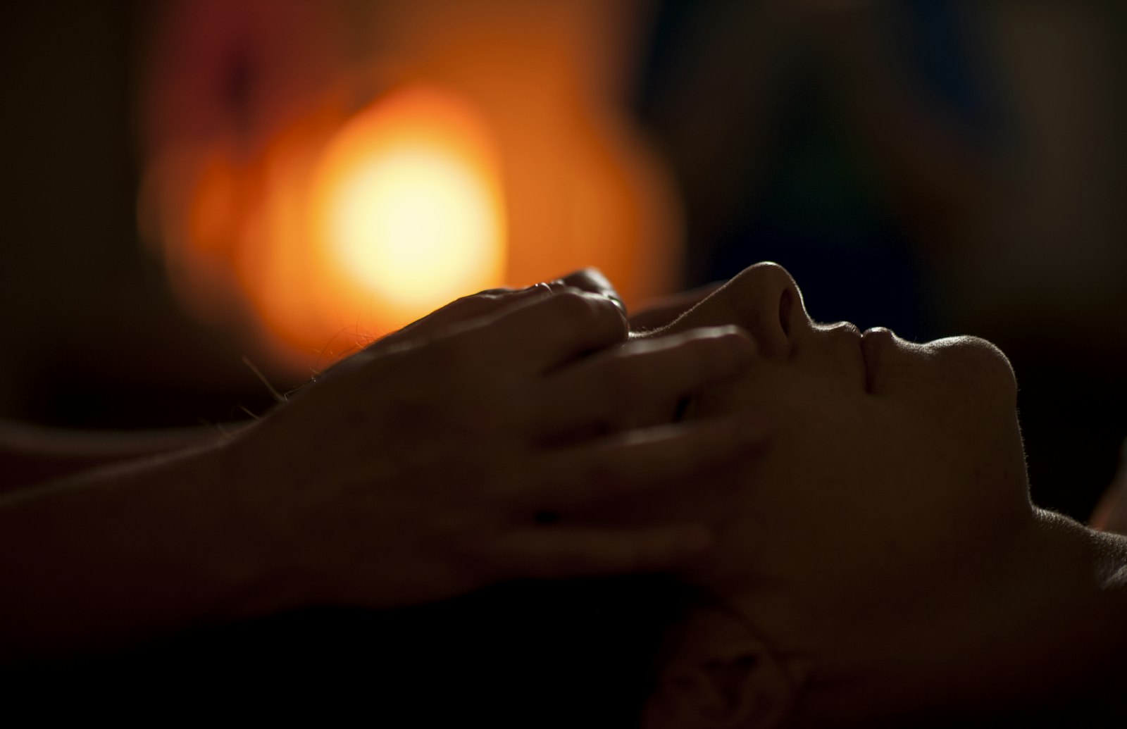 Hands massaging a face in warm low light