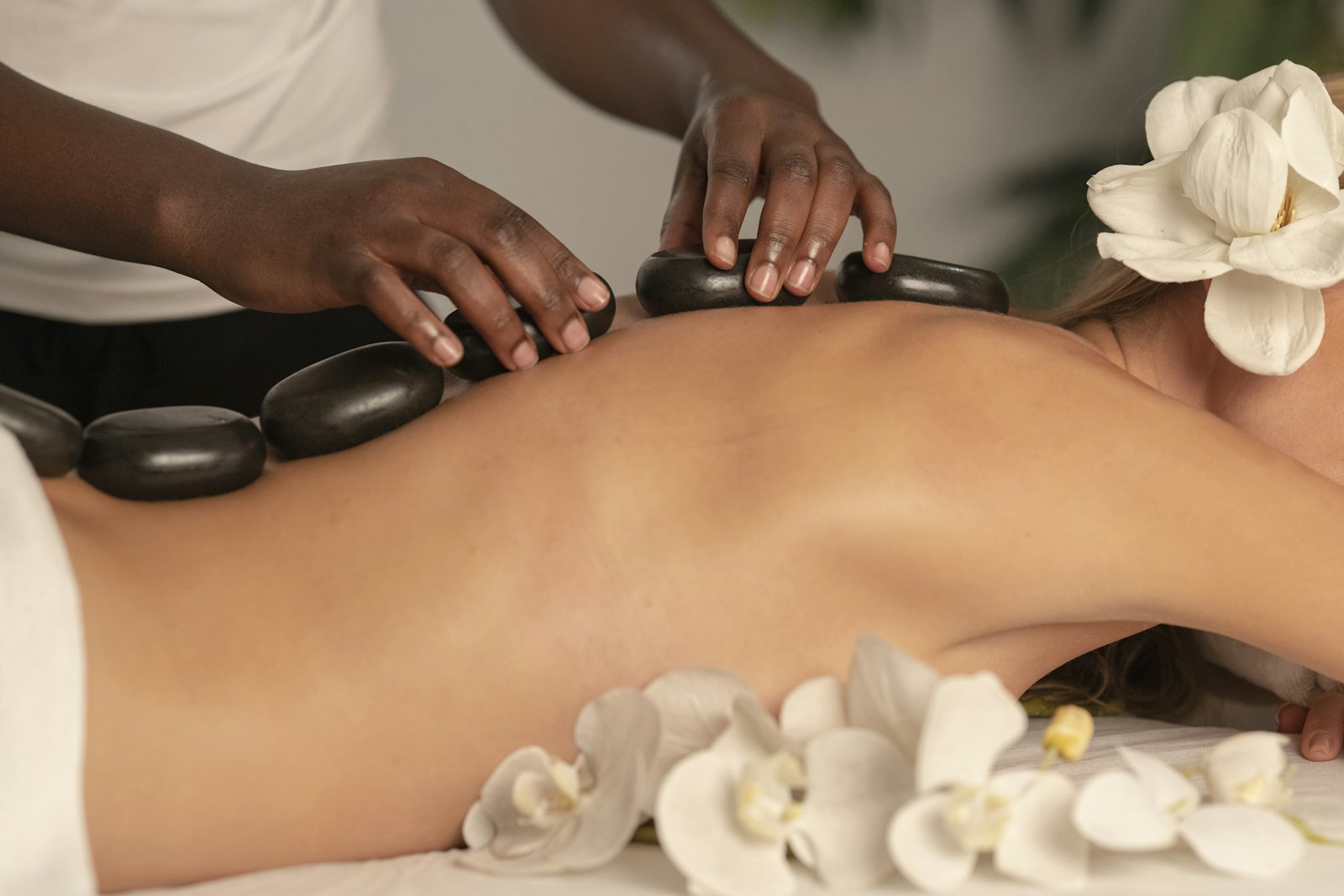 Hot basalt stones placed along a client's back on a massage bed