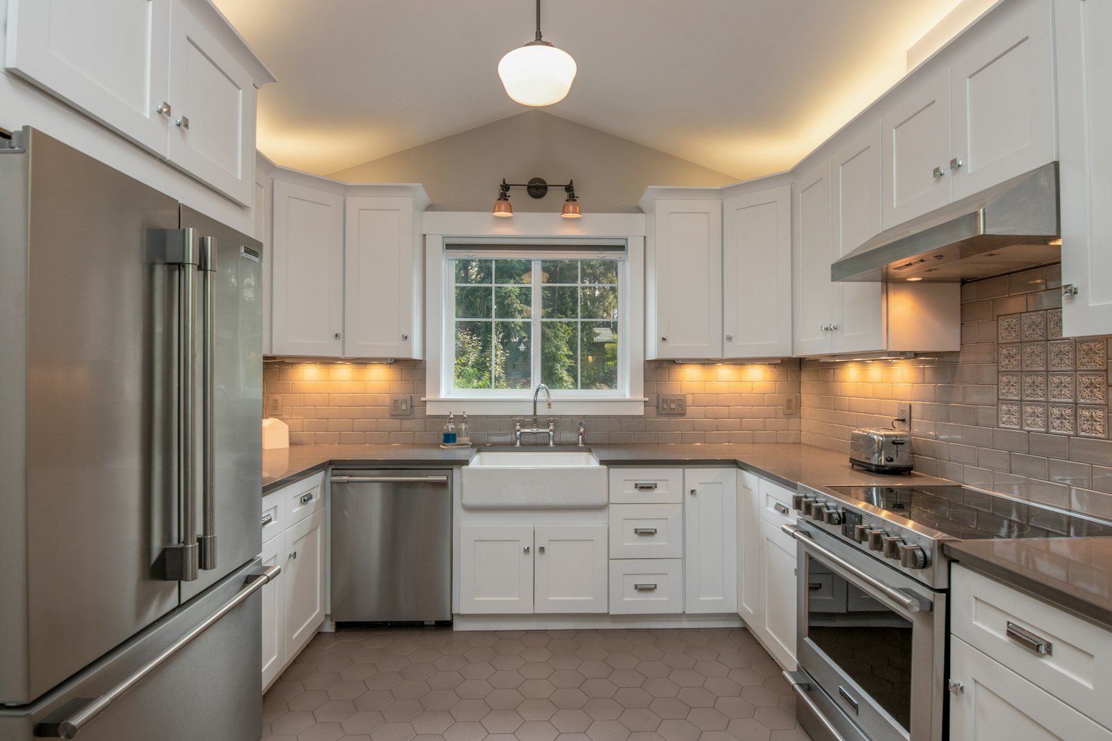 A finished white kitchen with pendant lamps over the island